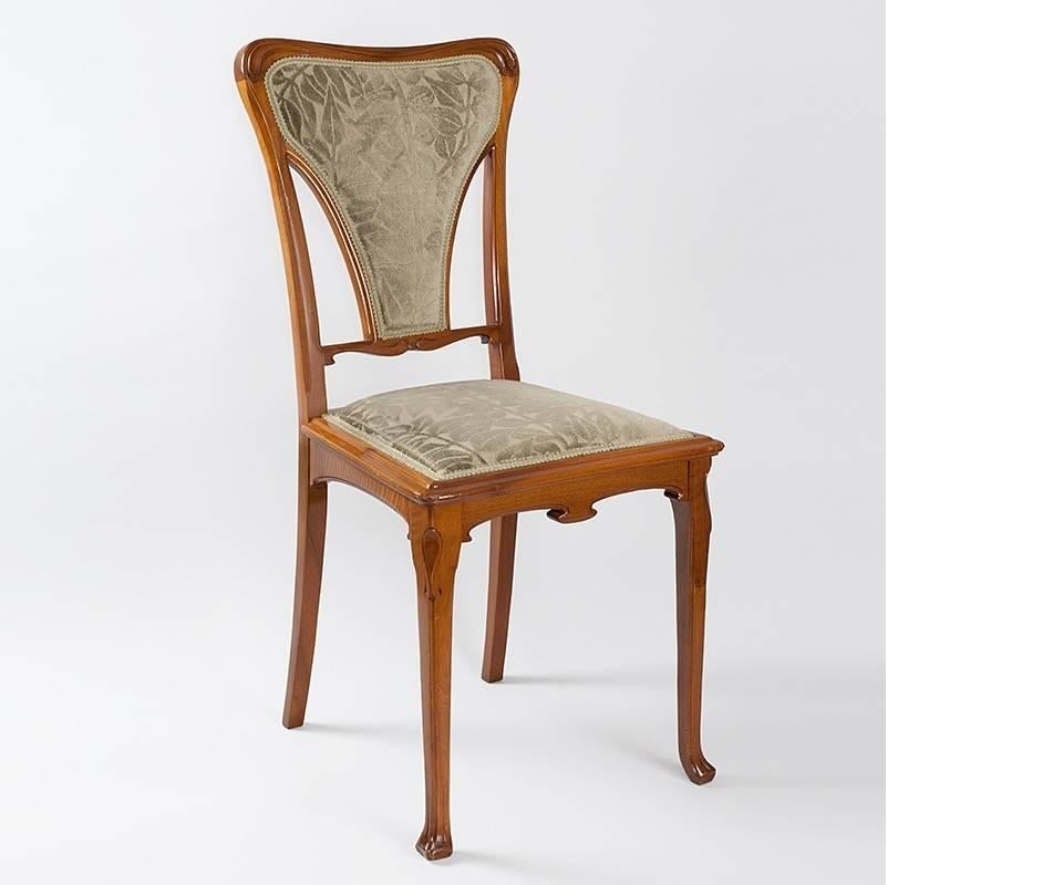 A French Art Nouveau upholstered chair by Gauthier. The chair's back and legs are gracefully carved, and the ornament in relief beneath the seat is repeated as carving in the chair back. The chair is upholstered in a leafy green fabric. 

(MG #17502)