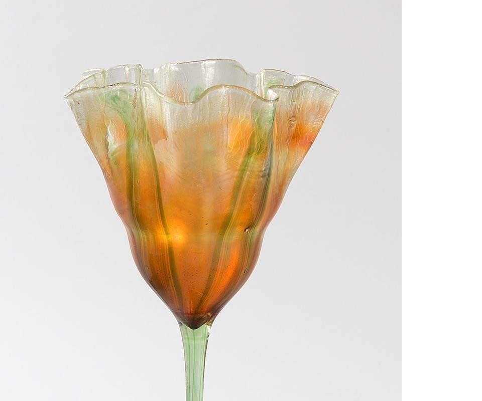 A Tiffany Studios New York glass “Flower Form” vase, featuring green foliage, translucent amber and orange Favrile glass, decorated with a floral motif. The stem ends in a golden amber/red iridescent base.

Favrile glass vases in the shapes of