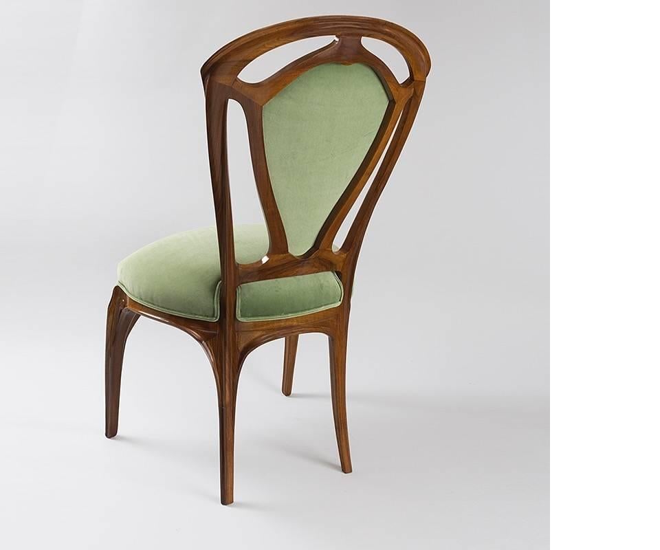 A French Art Nouveau carved wood side chair by Jacques Gruber. This unique chair has an unusual cut-out back, contrasting angular lines against its rounded outer edges. Exhibited at the Exposition de l'Ecole de Nancy in 1903., It is upholstered in