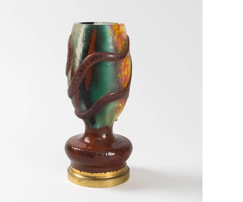 This cameo glass vase, by Ernest Leveillé for Escalier de Cristal, features two wheel-carved red serpents in high relief intertwined around the outer surface. The Art Nouveau serpents meet with animated expressions at the center of the composition,
