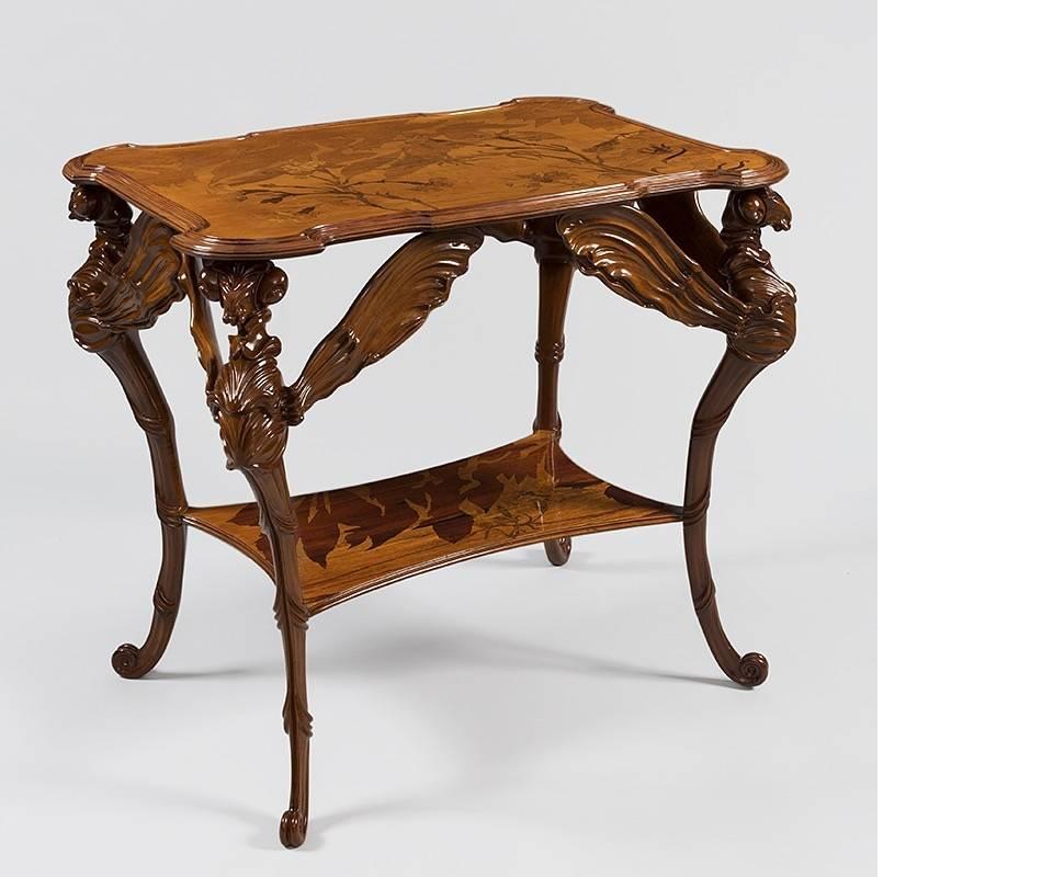 A French Art Nouveau two tiered table by Émile Gallé. The table's four legs are the carved bodies of dragonflies, their wings outstretched and frozen mid-flight. The table top rests on the dragonflies' heads and wings, with a fluid curvature in the