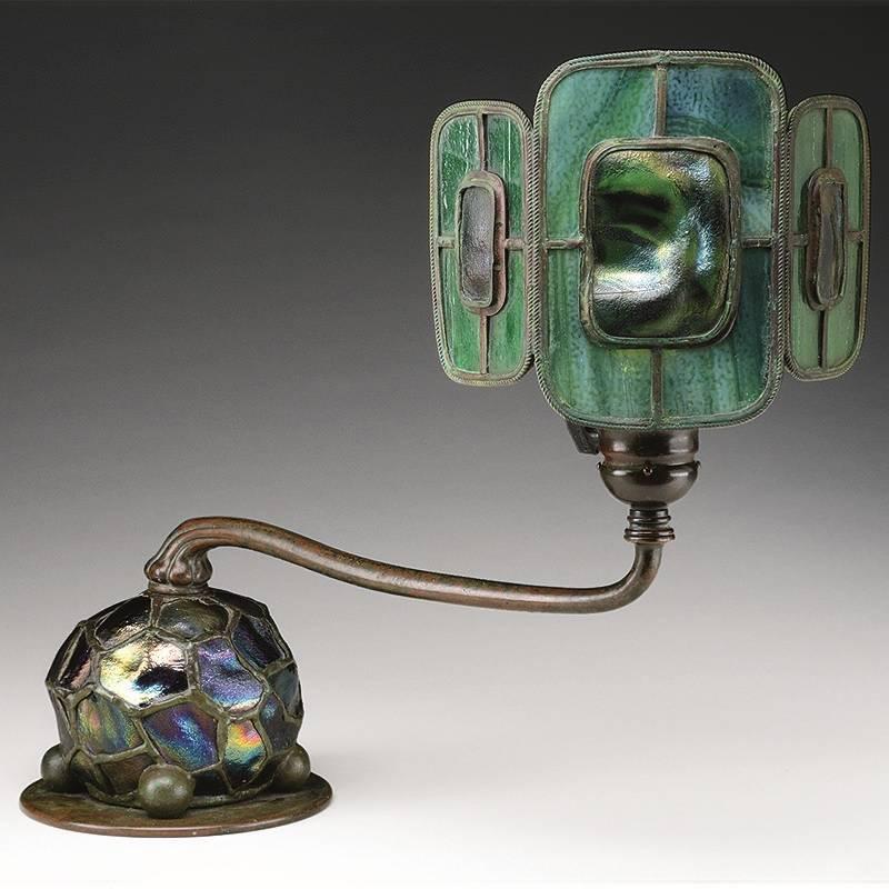 A Tiffany Studios New York "Turtleback Tile" leaded glass and bronze table lamp, circa 1900.

Provenance: From the Unreserved Estate of Lynda Cunningham.

A similar shade and base are pictured separately in: Tiffany Lamps and