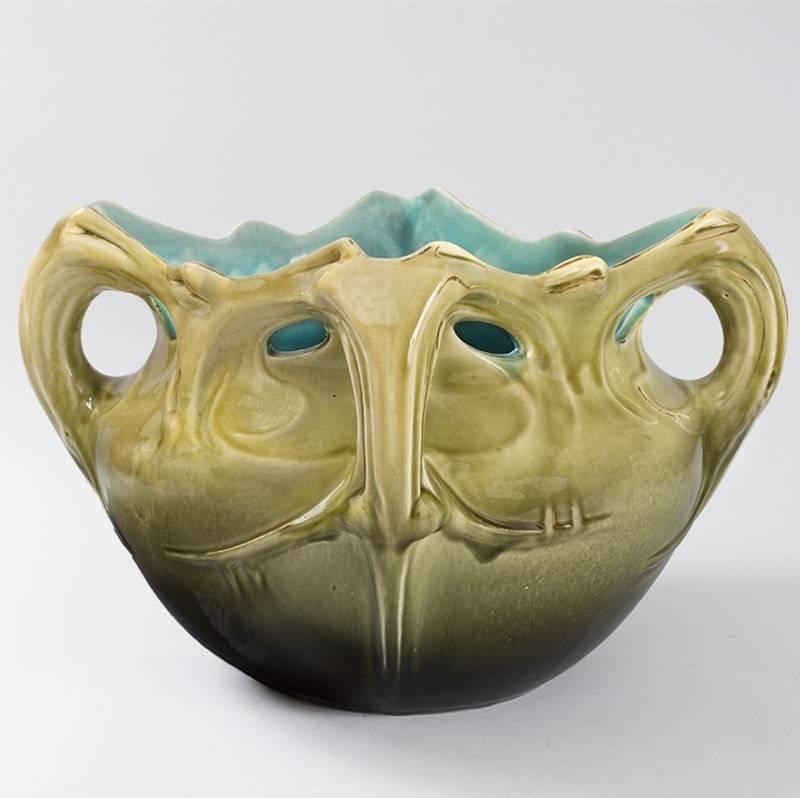 A French Art Nouveau green ceramic planter known as “Chalmont” by Hector Guimard.  The planter features a blue interior with stylized gold-highlighted handles. Circa 1890's.

A similar planter is featured in: Philippe Guimard Thiébaut edition of the