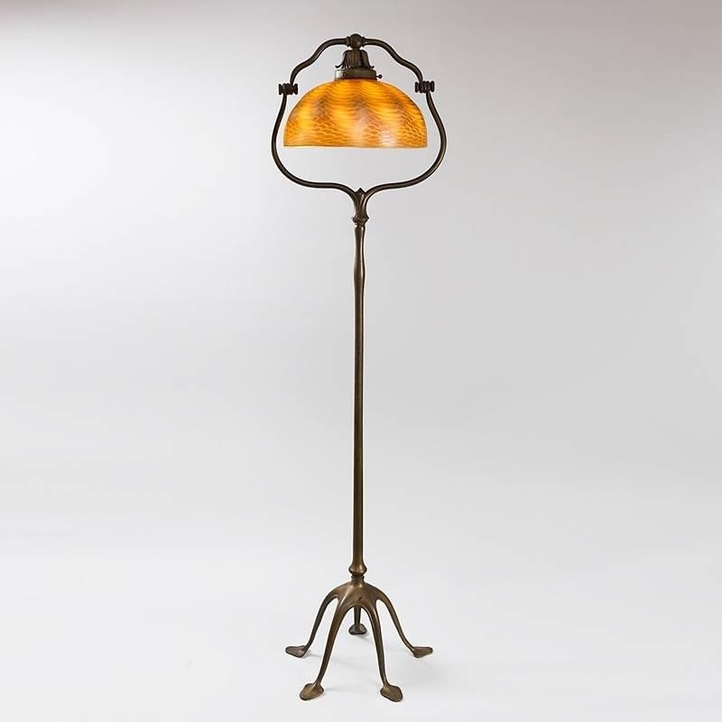 A Tiffany Studios New York Favrile glass and patinated bronze floor lamp with a golden “Damascene” shade with iridescent decoration suspended within a five-footed “Harp” base, circa 1900.

A similar shade and base are pictured separately in: