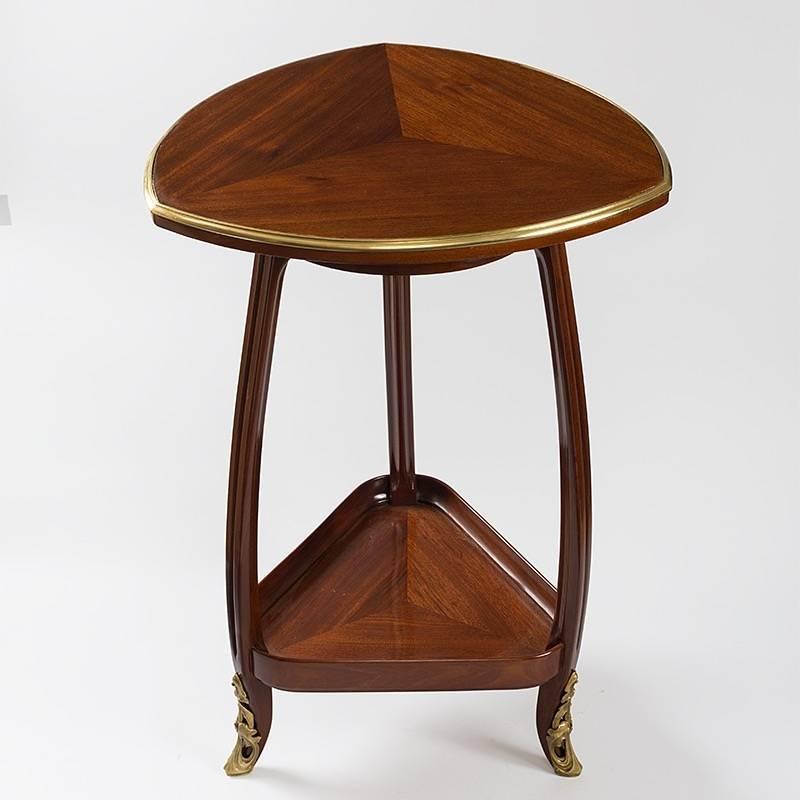 Ein dreieckiger französischer Jugendstiltisch von Louis Majorelle. Dieser zweistufige dreieckige Tisch ist aus Mahagoniholz gefertigt. Die geschnitzten Beine sind mit vergoldeten Bronzeschuhen versehen, um 1910.

Ein ähnlicher Tisch ist abgebildet