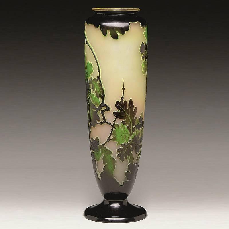 A French Art Nouveau carved cameo glass vase by Émile Gallé, decorated with oak leaves and a staghorn beetle.. On a background that changes gradually from pale yellow to pale orange, a brown staghorn beetle climbs a brown branch toward green leaves.