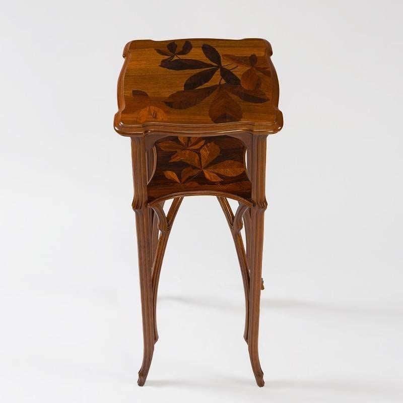 A French Art Nouveau two-tiered square pedestal with carved and marquetry decoration by Emile Gallé. The pedestal has two marquetry shelves depicting leaves. Its four sinuous legs are enhanced with carved arch supports, circa 1900.

A similar