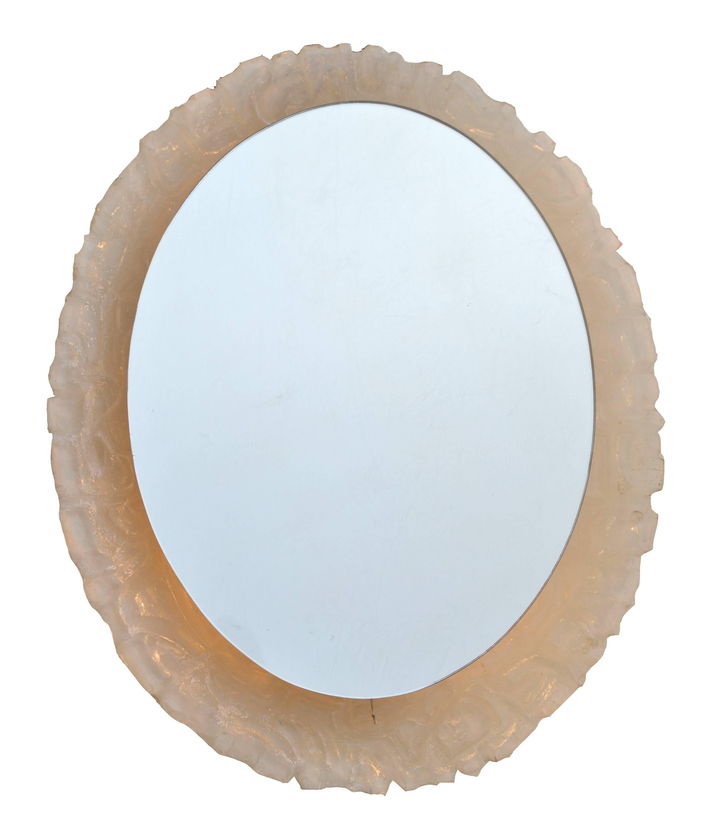 An architecturally crafted in a textural molding surround, this oval round mirror is cast of clear citron or resin with backlit lighting. Recently rewired.