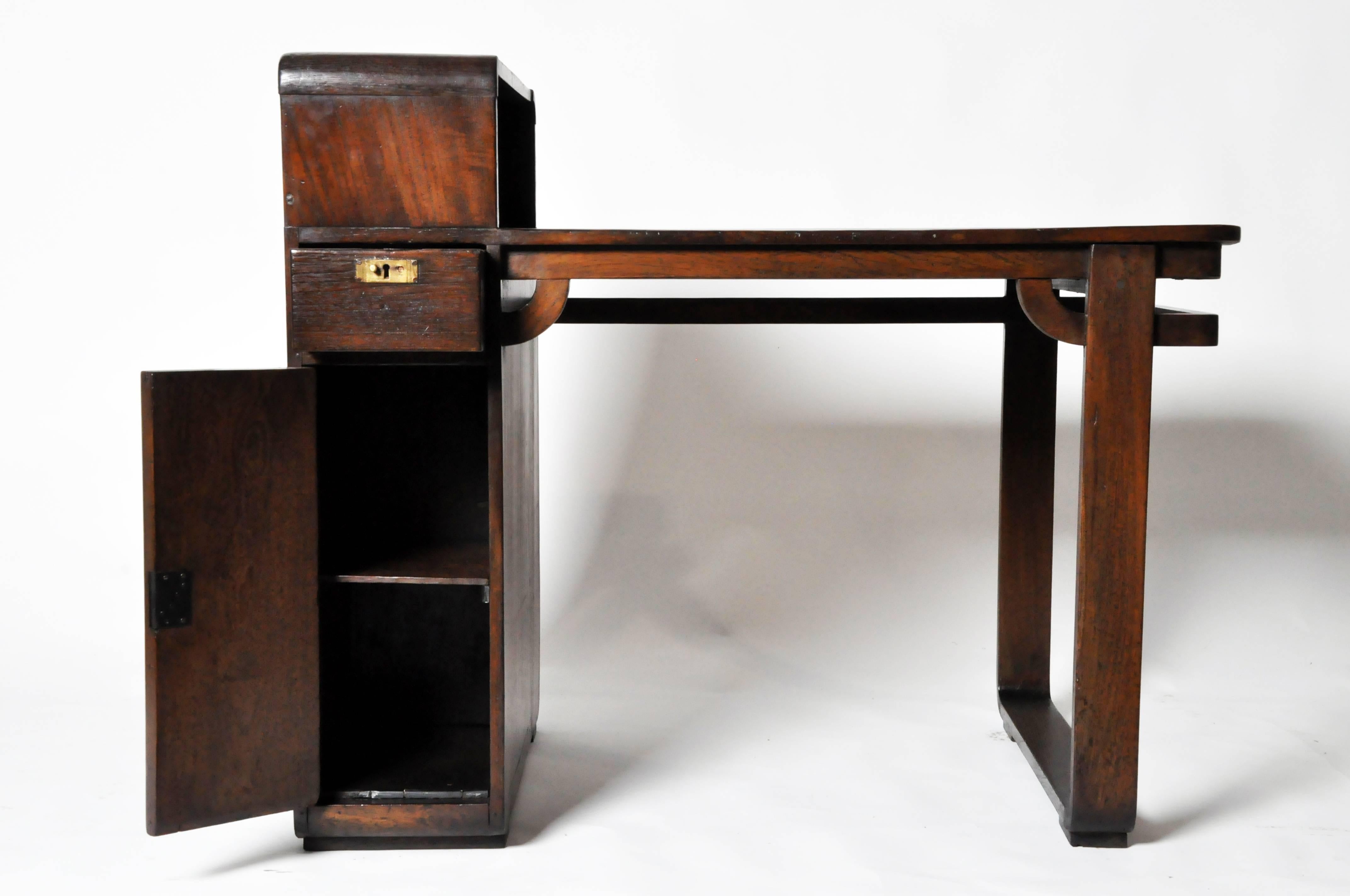 Influenced by the geometric forms of Art Deco and the curvaceous lines of Modernist design, this single pedestal desk channels elements from both styles. The left leg is comprised of a single drawer over a storage compartment that opens on either