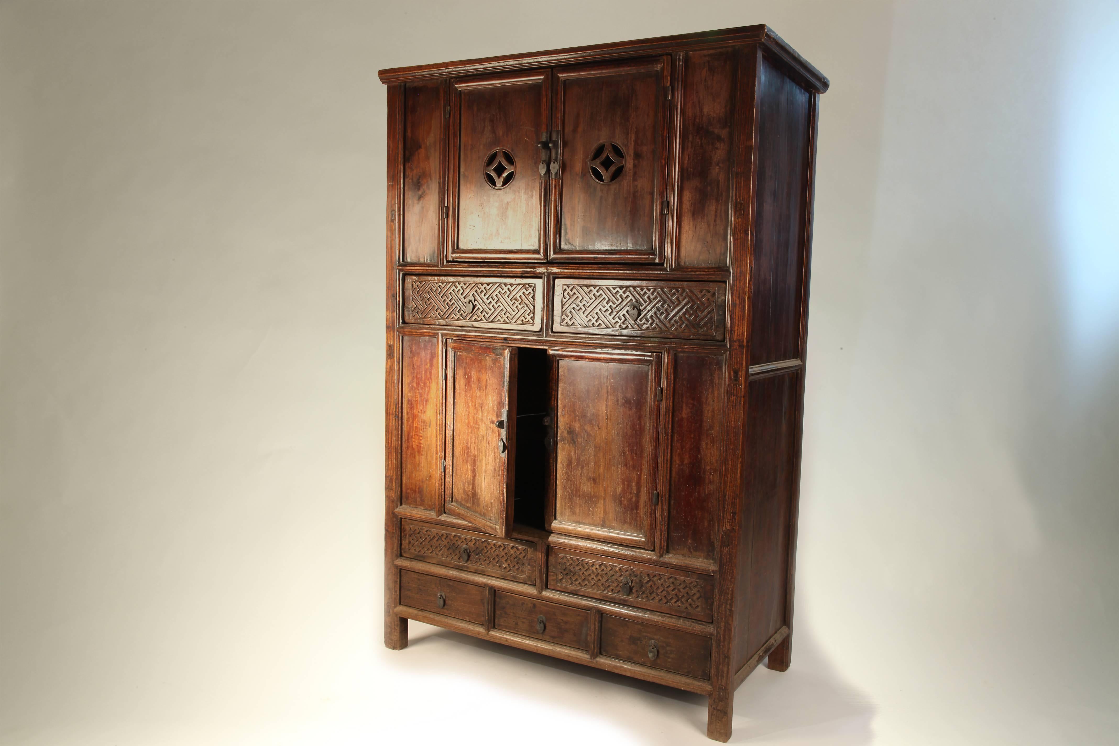 This handsome wardrobe features two storage compartments, each housing a single removable shelf covered by a pair of doors of which the top set has pierced-carved medallion-and-diamond decoration. Additional storage comes in the form of seven