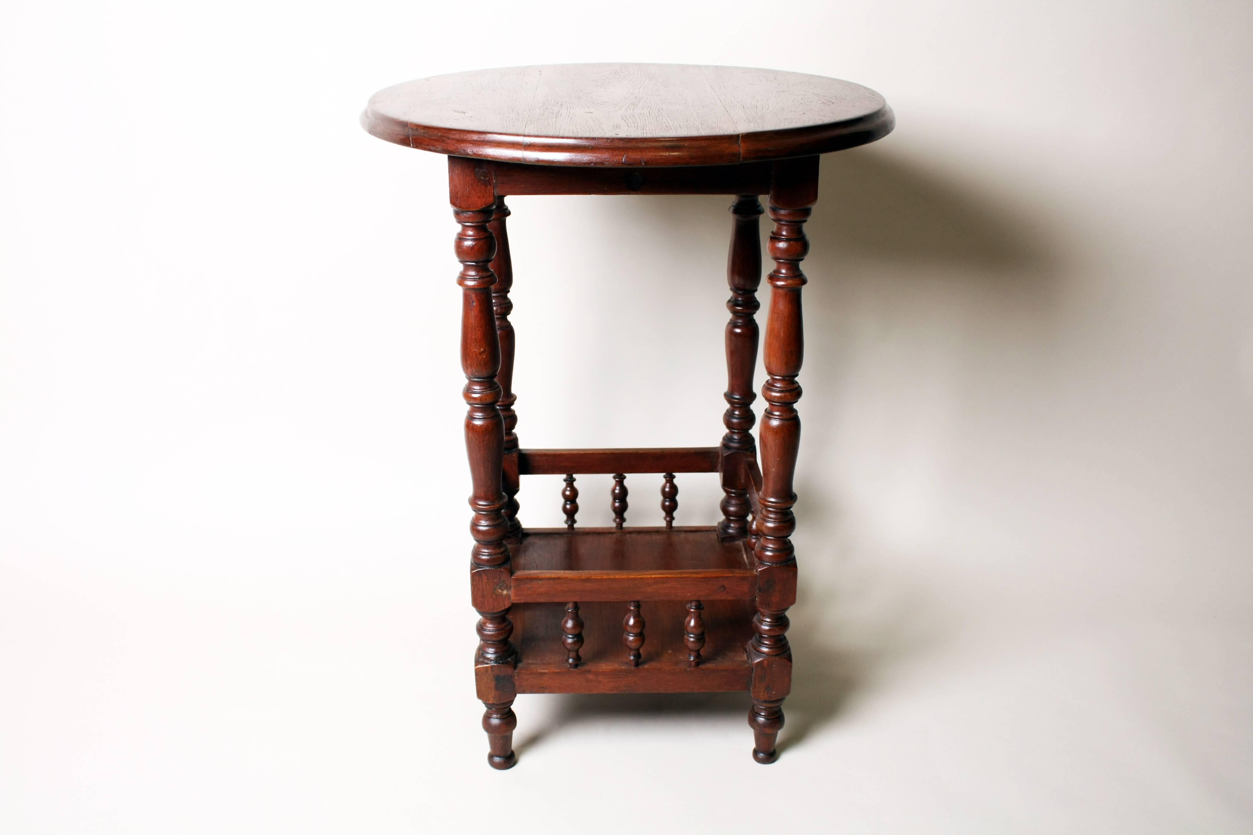 Charming and compact this beautiful table features a circular top supported by shapely turned legs. A secondary storage area comes in the form of a square lower shelf that is framed by turned spindles. Given its rich detail, this sturdy piece has a