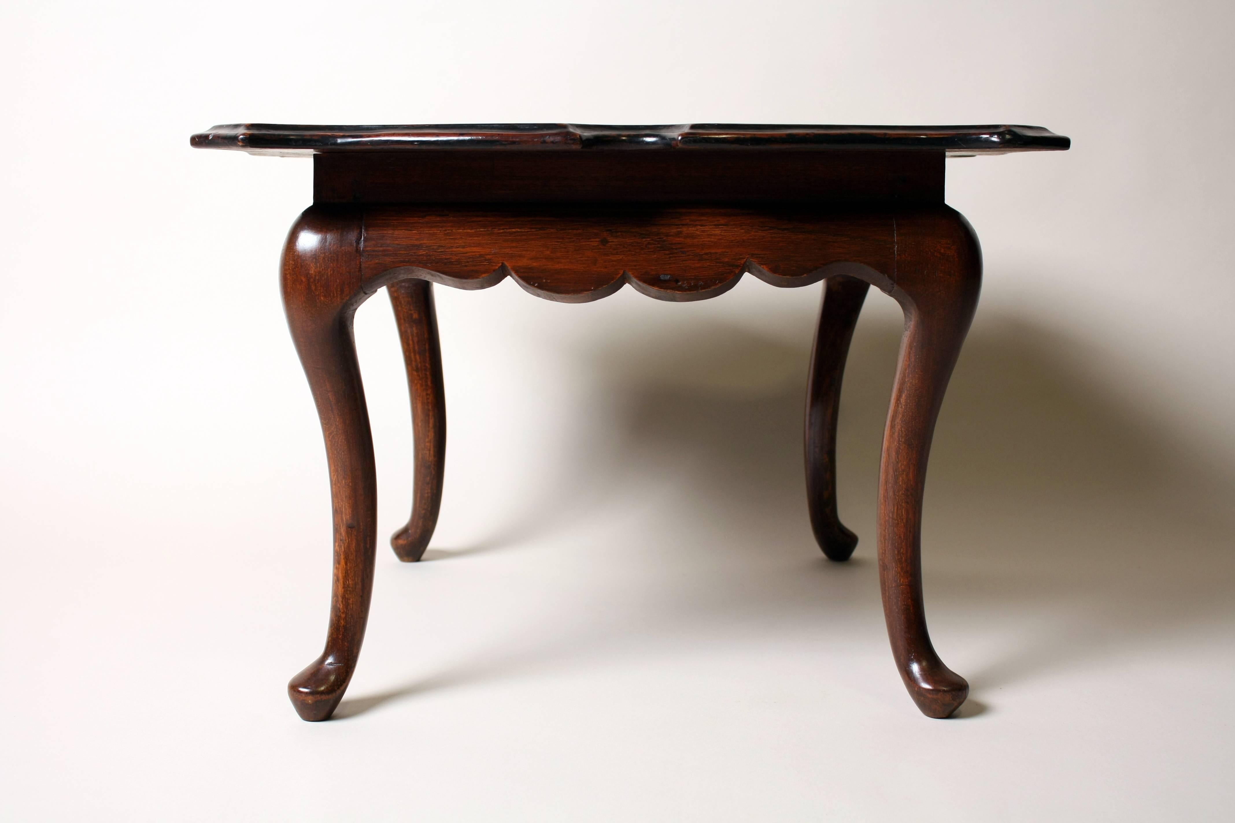 This short table features a square top with moulded, stepped edges; the graceful lines continue in the carved aprons, which are flanked by curvy cabriole legs in each corner.