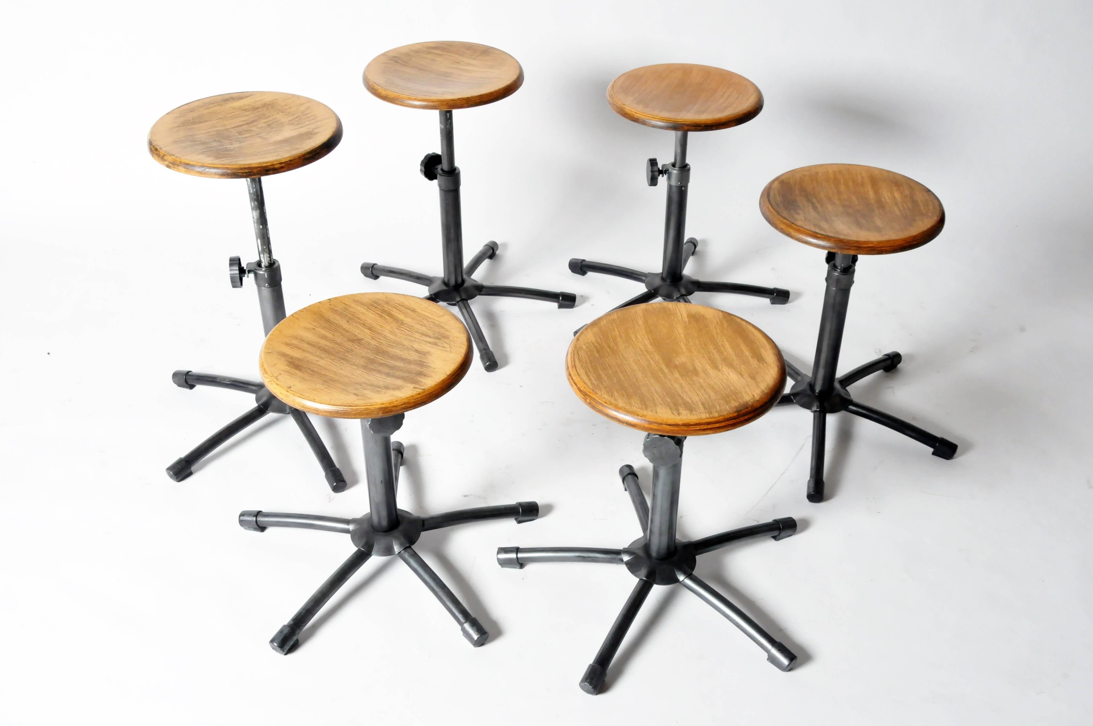 The circular wood seat is raised on an adjustable stem supported by five splayed, tubular legs. Six total, discount available if purchased as a group; measurements reflect stool seat fully extended.