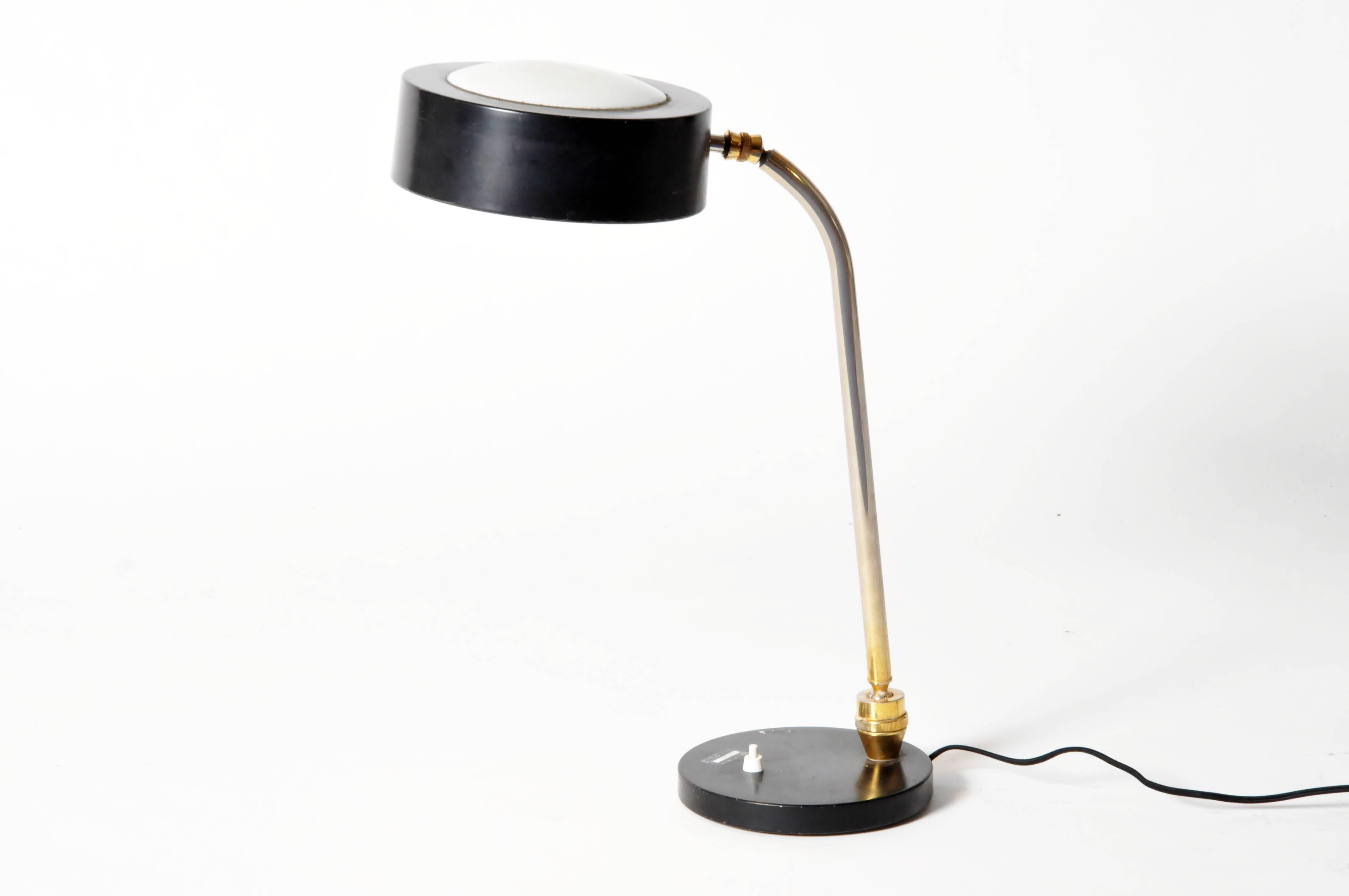 This smart task light features a cylindrical shade with an opaque dome, the articulated head and tubular chrome neck connect to the lacquered, plate like base.