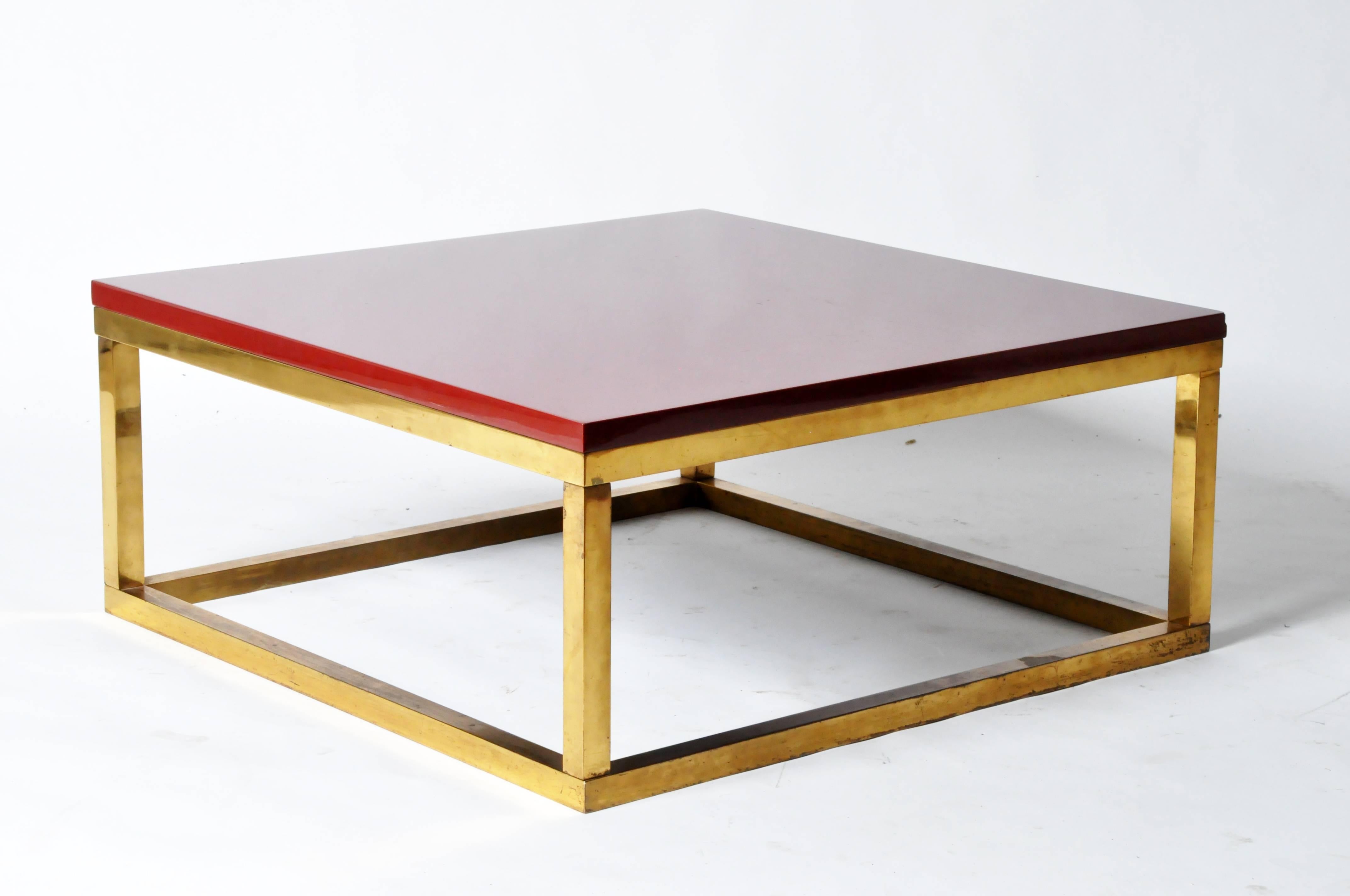 This handsome cube-like coffee table features a bright red top supported by rectangular brass frame, which is joined by base stretchers.