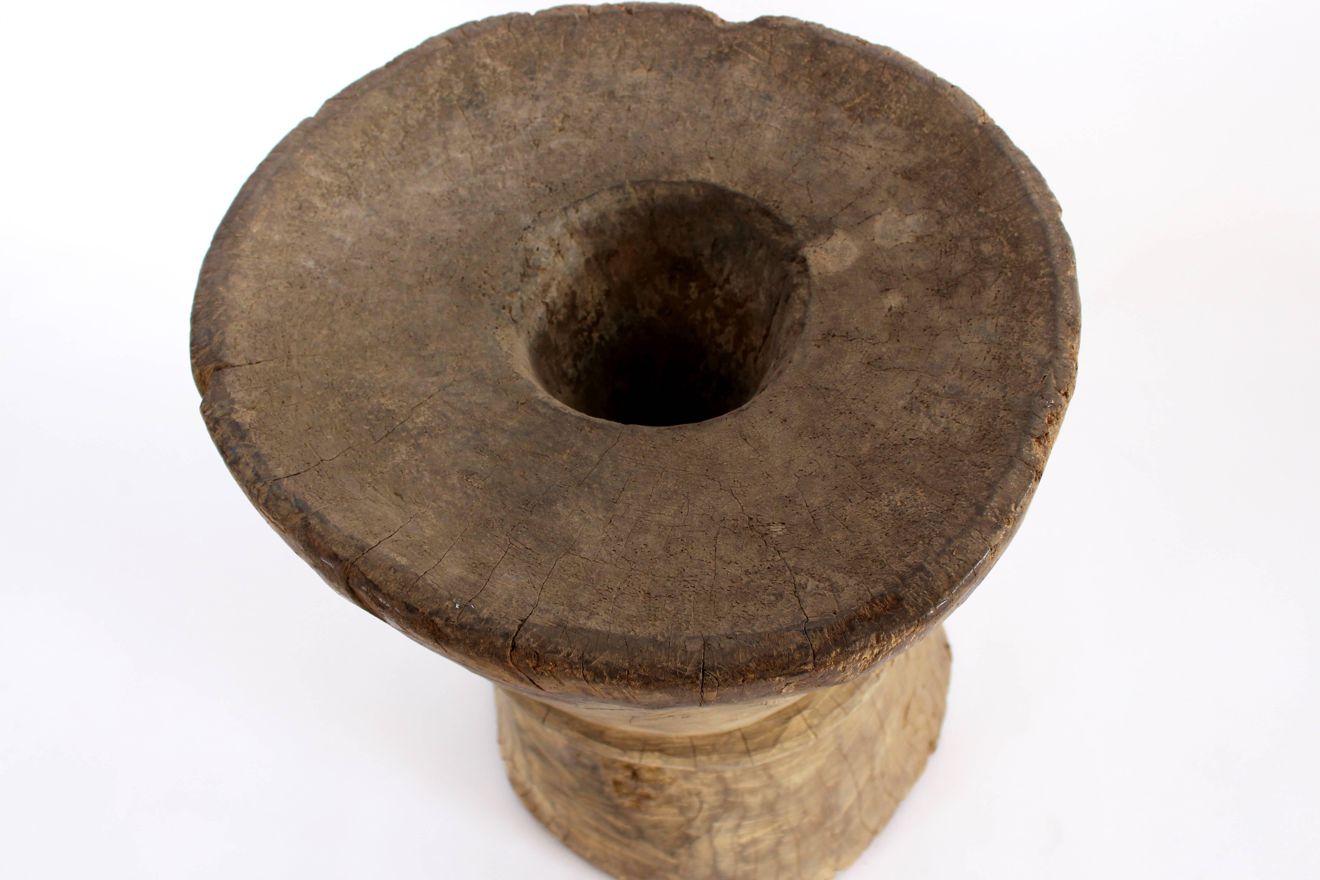 This hourglass shaped mortar has a band decoration around the middle and is accompanied by a carved pestle. The wide top features slightly raised edges and a single hole through its centre.

The Naga are an agriculturally based society. Not only