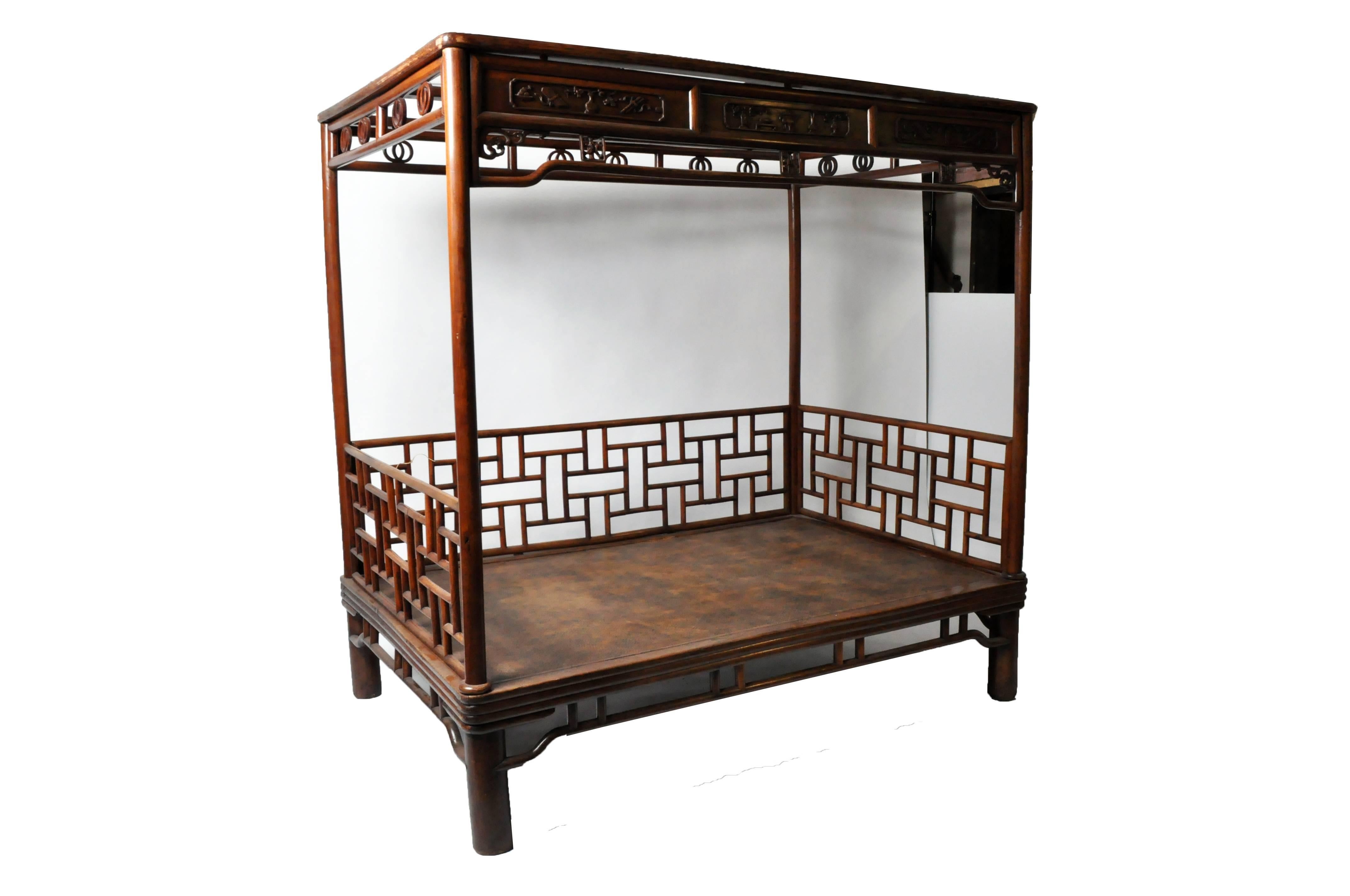 Elmwood (Jumu) bed, circa 1850. Ming style, with subtle decoration. The round posts of the bed platform and canopy suggest tree branches. Originally oxblood lacquer. Cane bedding has been replaced but expertly tee oven with jute webbing for support.