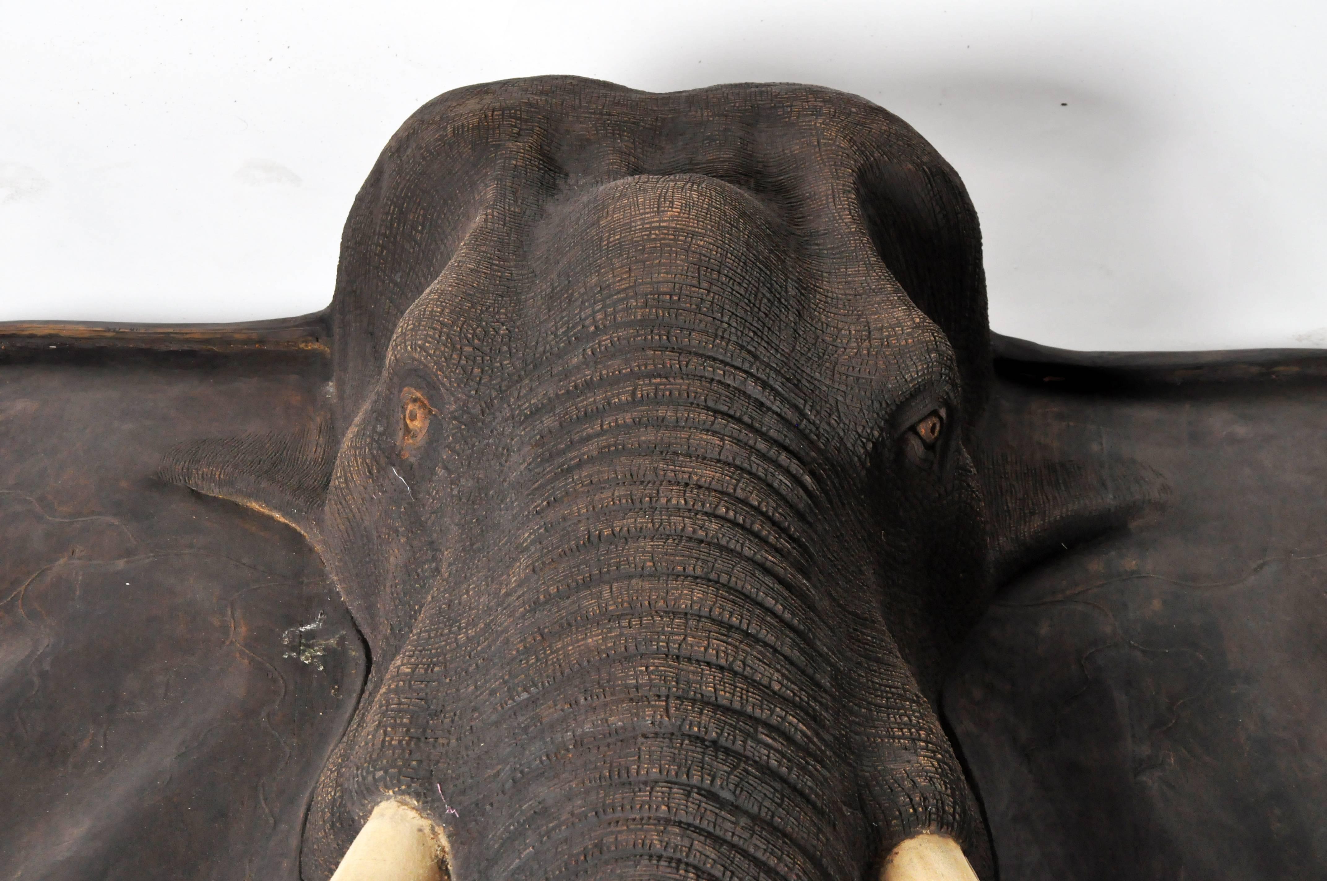 This monumental hand-carved elephant head is made from teakwood and is from Thailand. The details in the sculpture are intricate and life-like.
