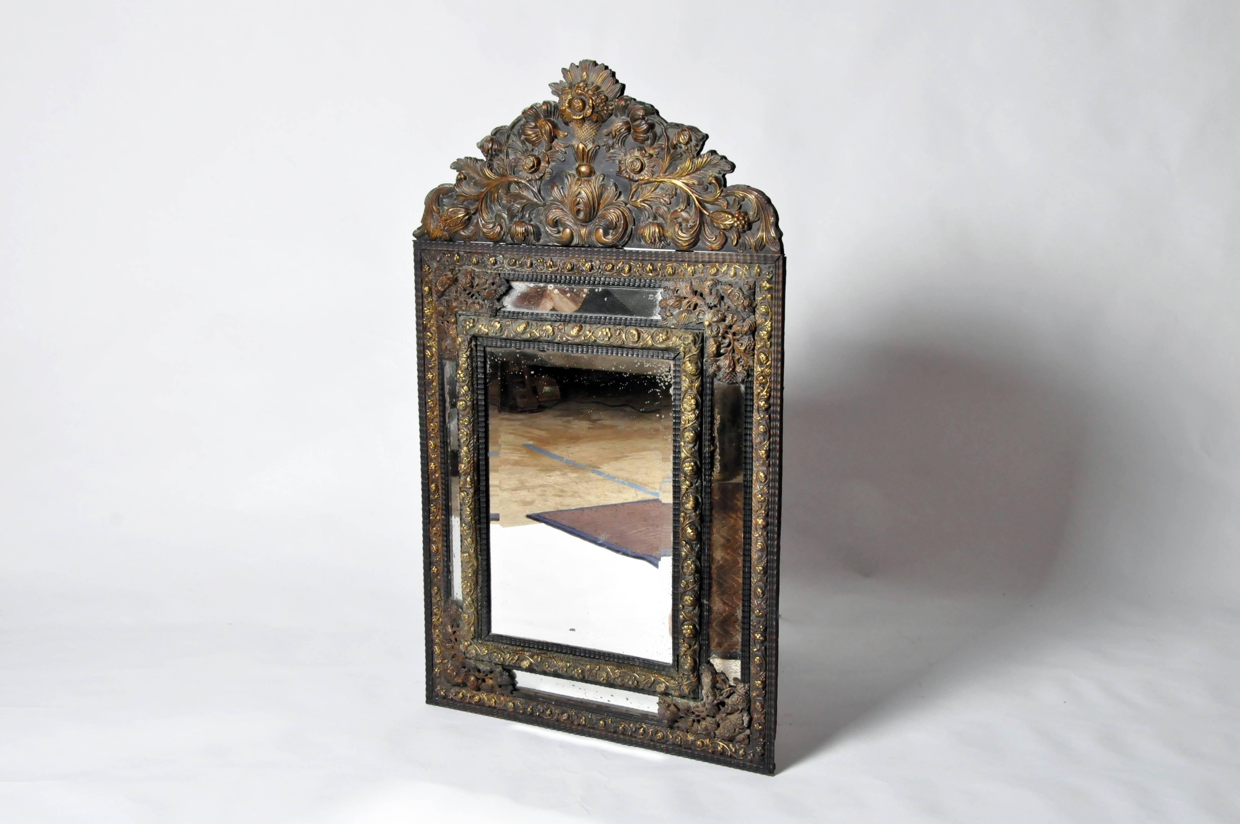 Brass frame with arched top and repousse decoration, rectangular beveled mirror plate. Exceptionally fine brass repousse supplemented with another metal, possibly copper. The quality of decoration makes earlier than 19th century date plausible.