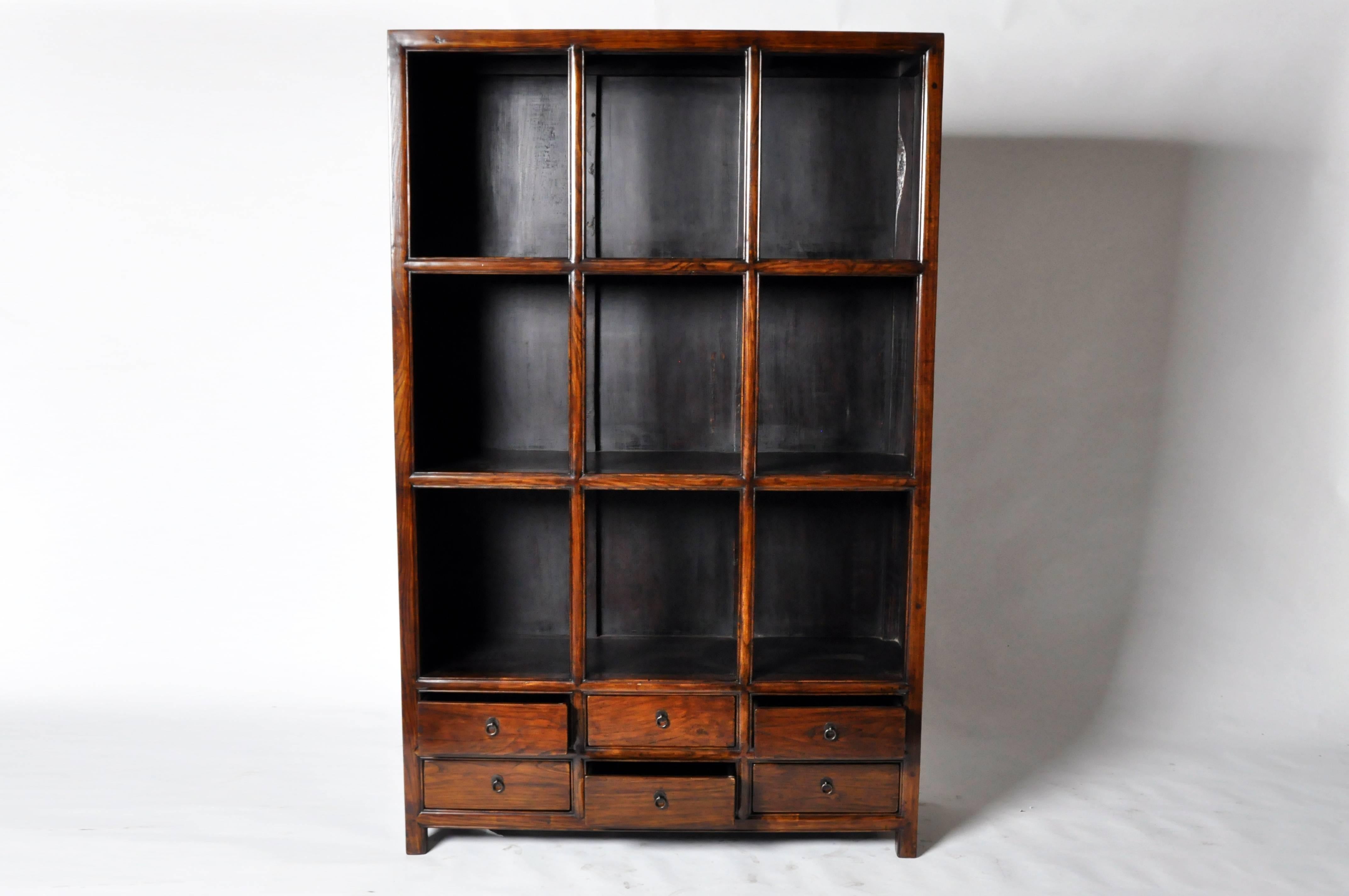 This impressive Chinese display cabinet is made from elmwood with some restoration. It features ample display shelves and six drawers for storage.