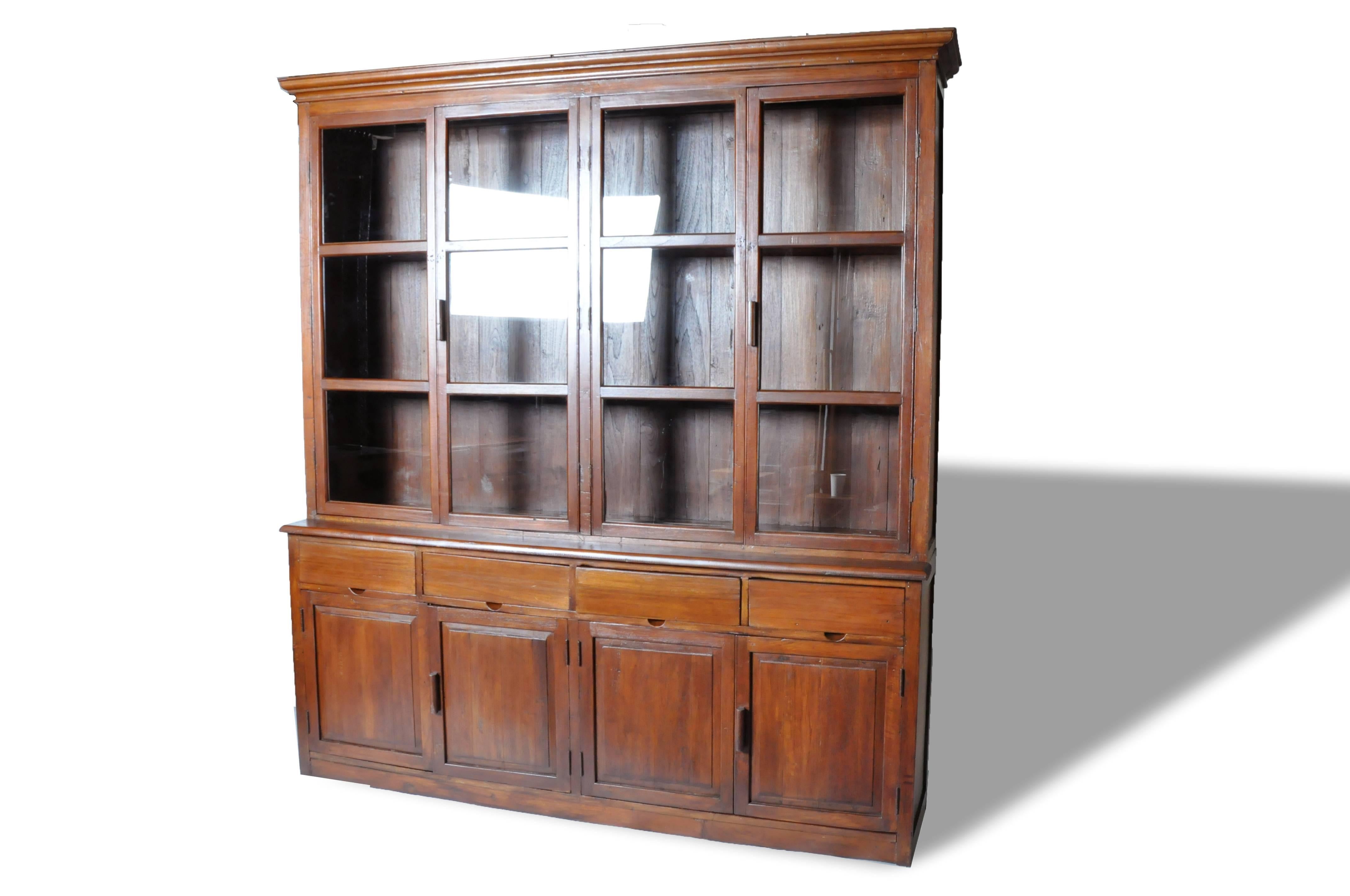 This impressive British Colonial cabinet comes in two parts; the top part features a display case that has two pairs of glass paned doors that open to compartments lined with shelves while the bottom section boasts ample storage space in the form of