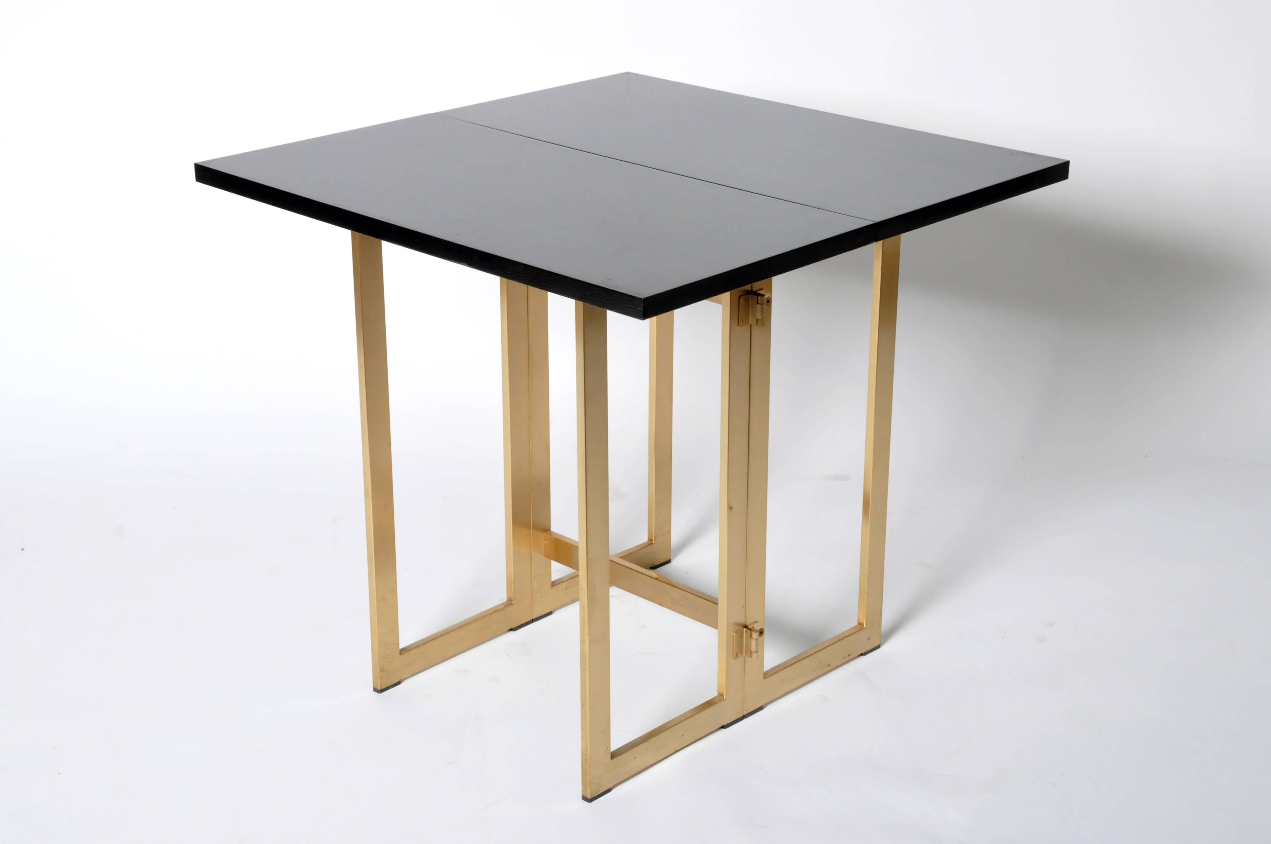 This folding black console table is from France and is made from oak veneer and has folding brass legs.
