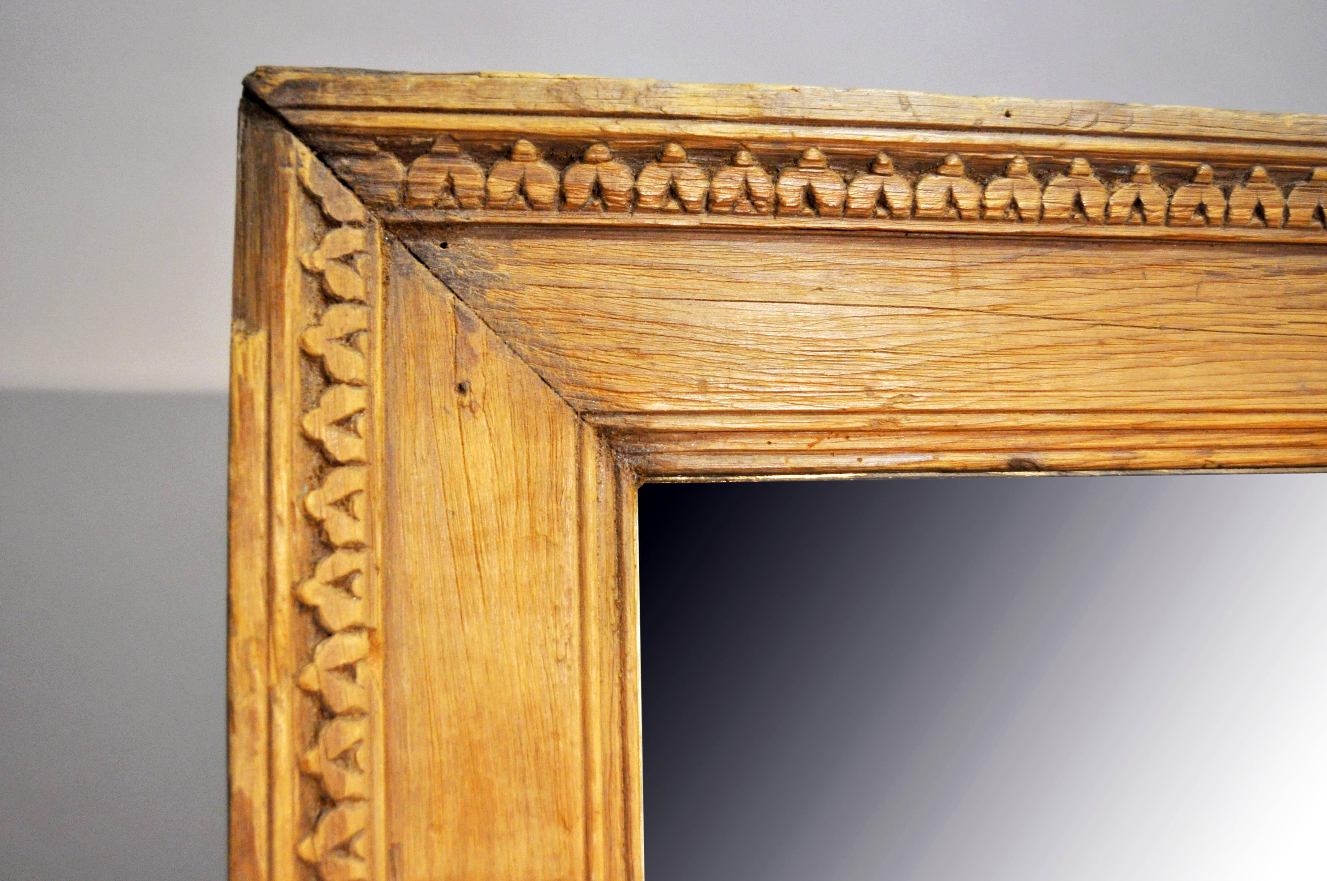 Natural and unfinished, the simple carved molding that frames the rectangular mirror plate is made from high-contrast grain.
