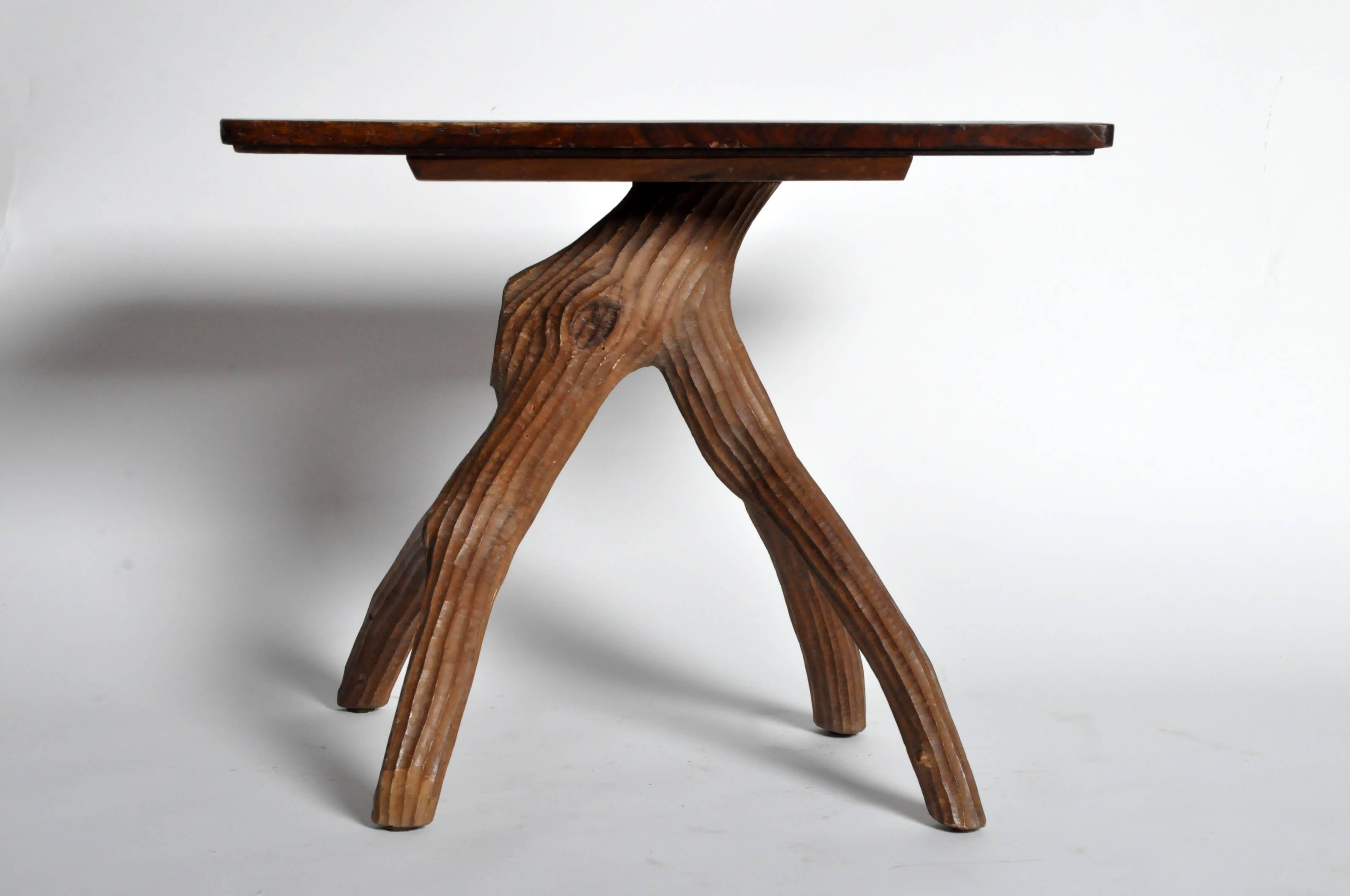 The rectangular top rests on a naturalistic tree branch-form carved table base that is sure to add rustic charm to any space.