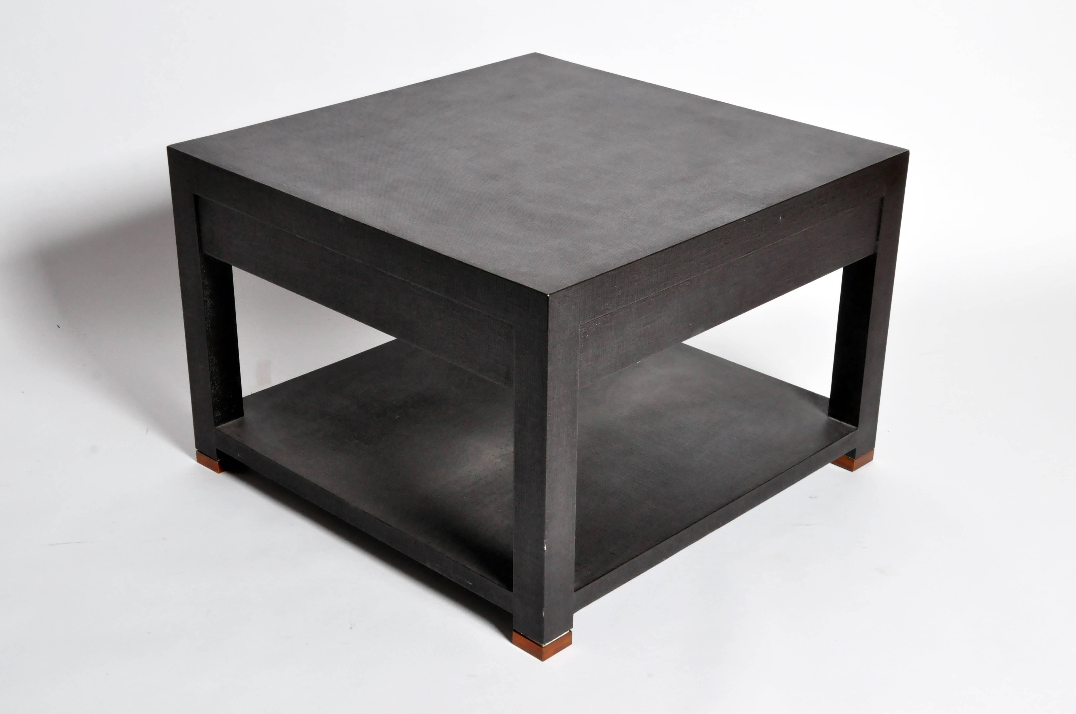 This modern brown low table is made in the U.S.A. and features a shelf and a drawer for display and storage. The bottom of the legs features brass mounts. Made from lacquered linen over wood and plywood. 