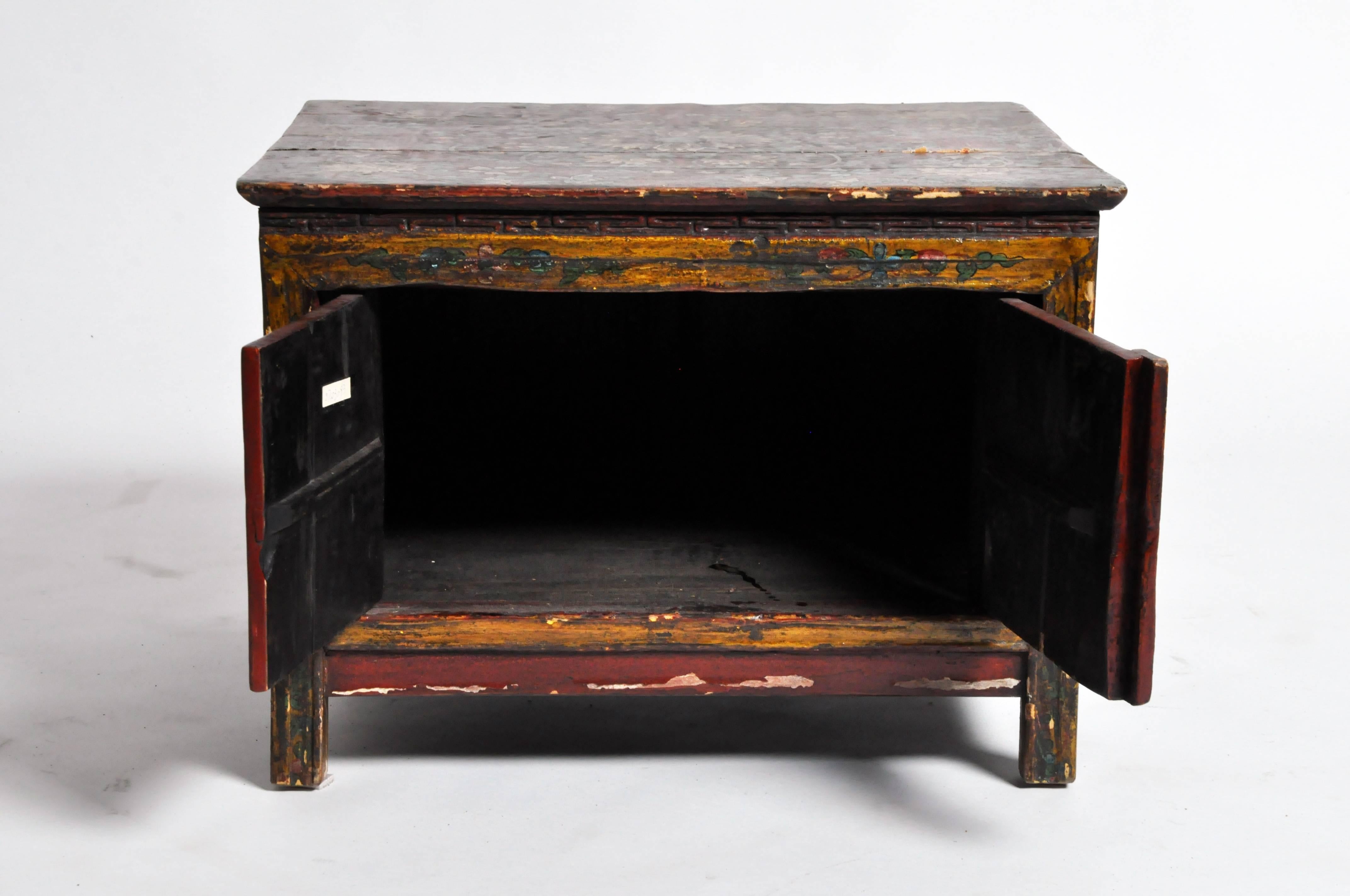 This low cabinet is from Tibet and is made from fir wood and lacquer. The piece features hand-painted flowers, 19th century.