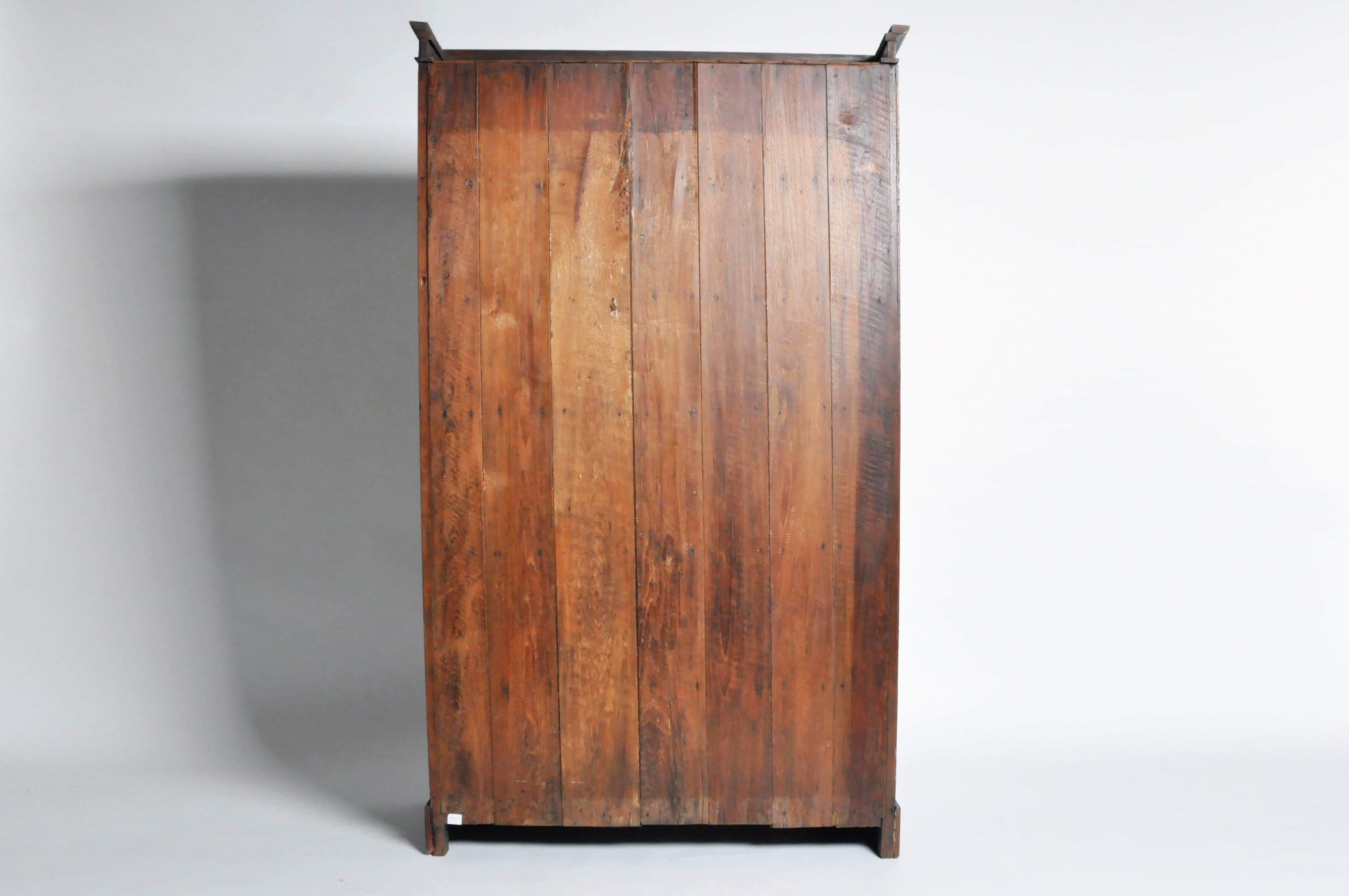 This handsome British Colonial bookcase is from Mandalay, Burma and is made from teak wood, circa mid-1900s. This cabinet comes in two parts, both featuring a set of sliding glass panel doors that open to compartments lined with shelves. The