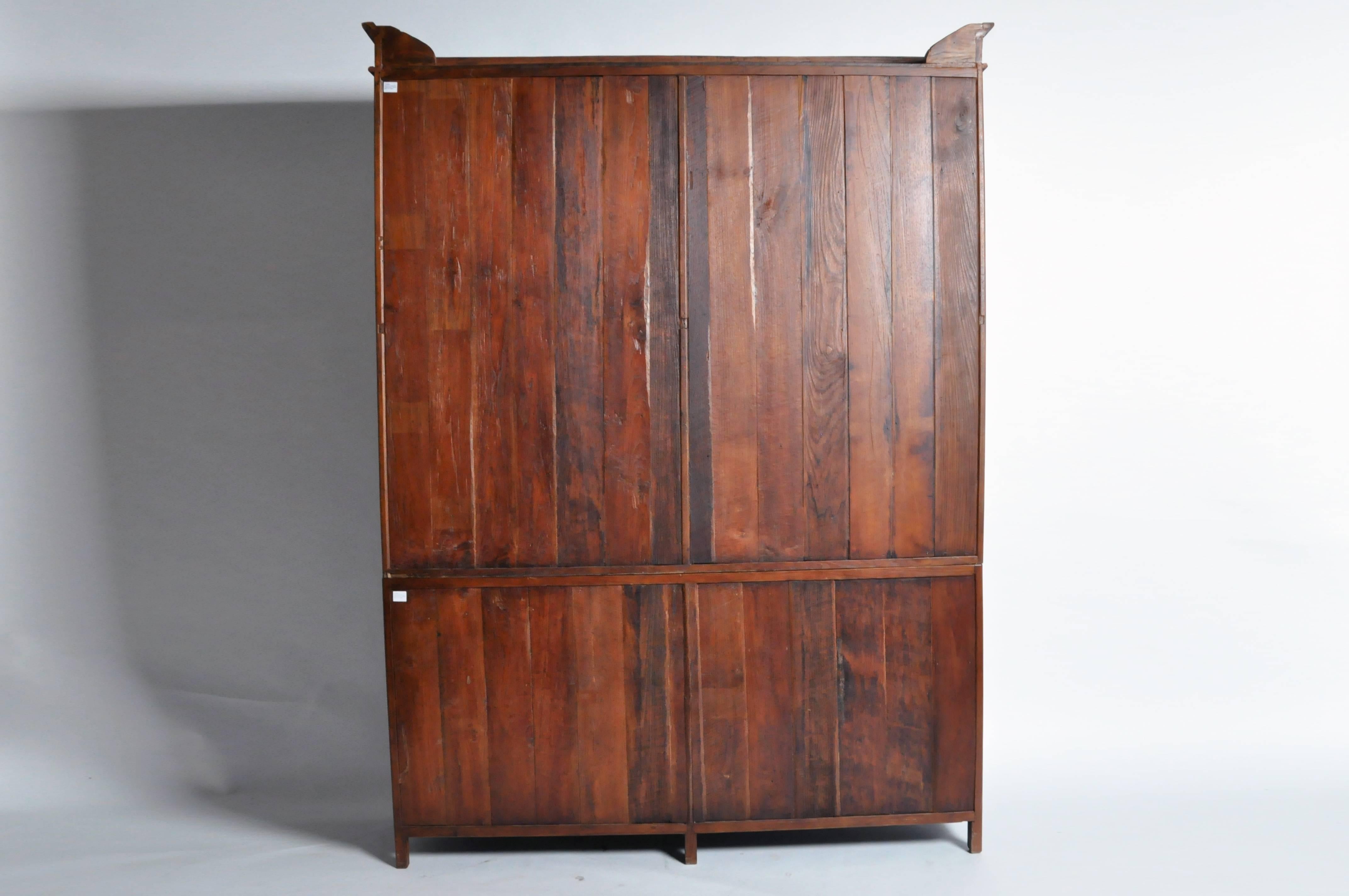 This important Burmese British Colonial cabinet comes in two parts, the top having a stepped cornice over two sets of glazed doors and the lower section featuring two pairs of glazed doors with horizontal teak mullions. Both open to compartments
