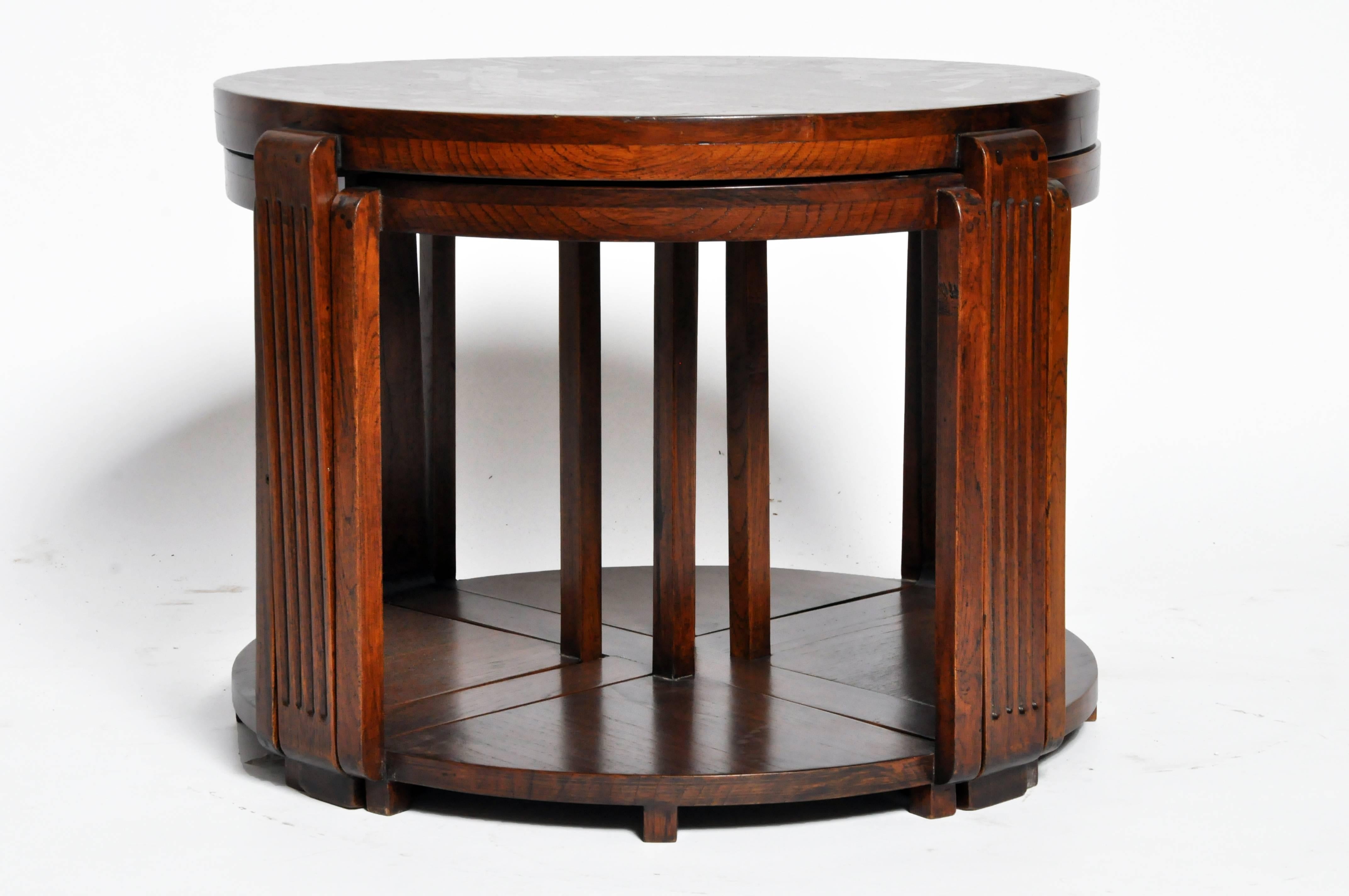 This impressive British Colonial round table is from Rangoon, Burma and is made from teak wood. The veranda center table features four small nested side tables that can be used as seats for the table and has its original finish.