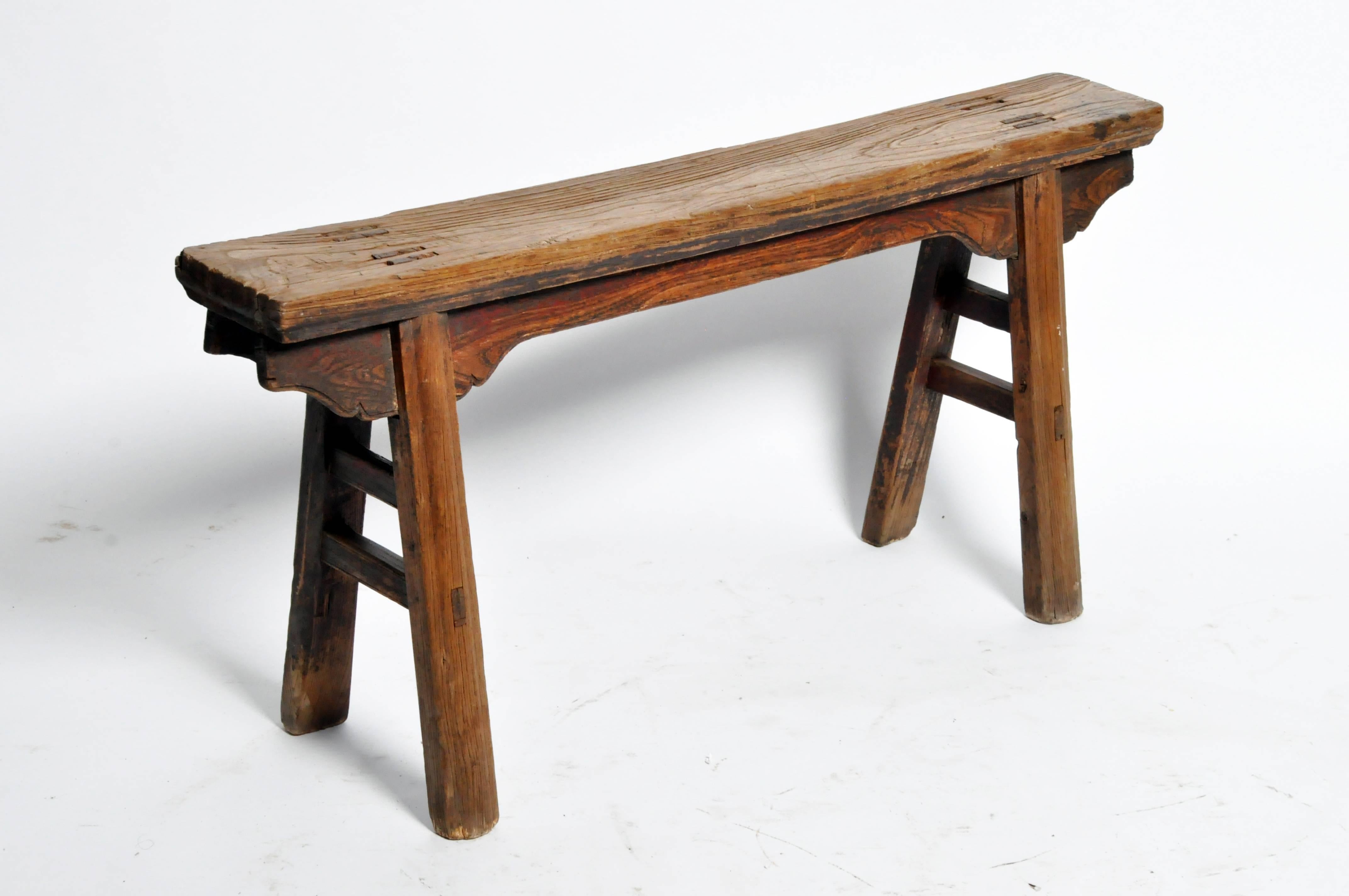An elmwood bench from Shanxi, China that dates to the late Qing dynasty. The rectangular legs with recessed molding and carved spandrels add simple detailing to quality mortise and tenon construction.