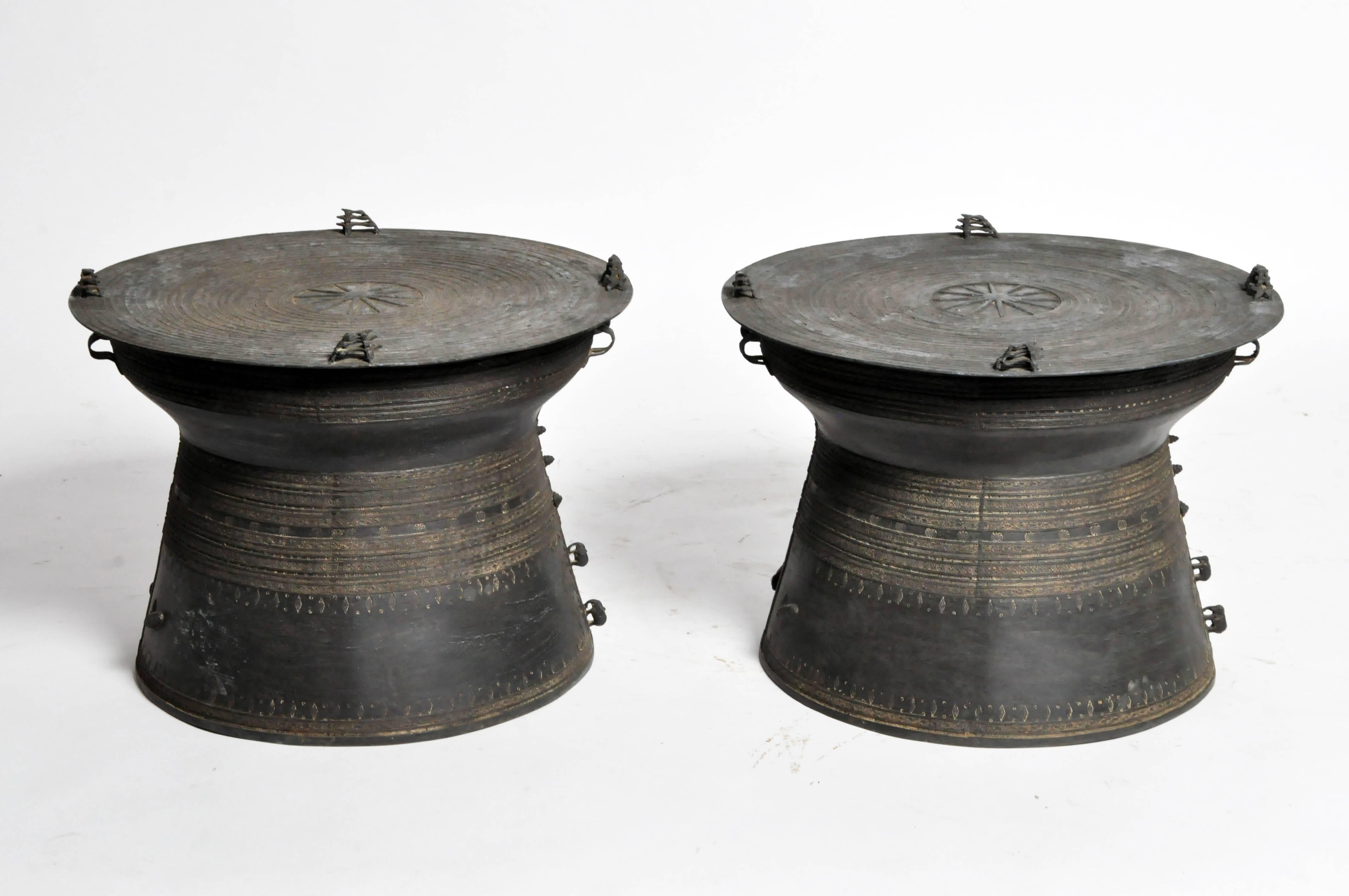 These handsomely patinated drums have circular tops with four double frog-form handles. Decorated with radiating bands and geometric patterns throughout, the waisted bodies are flanked by loop handles while their bases feature large leaf outlines
