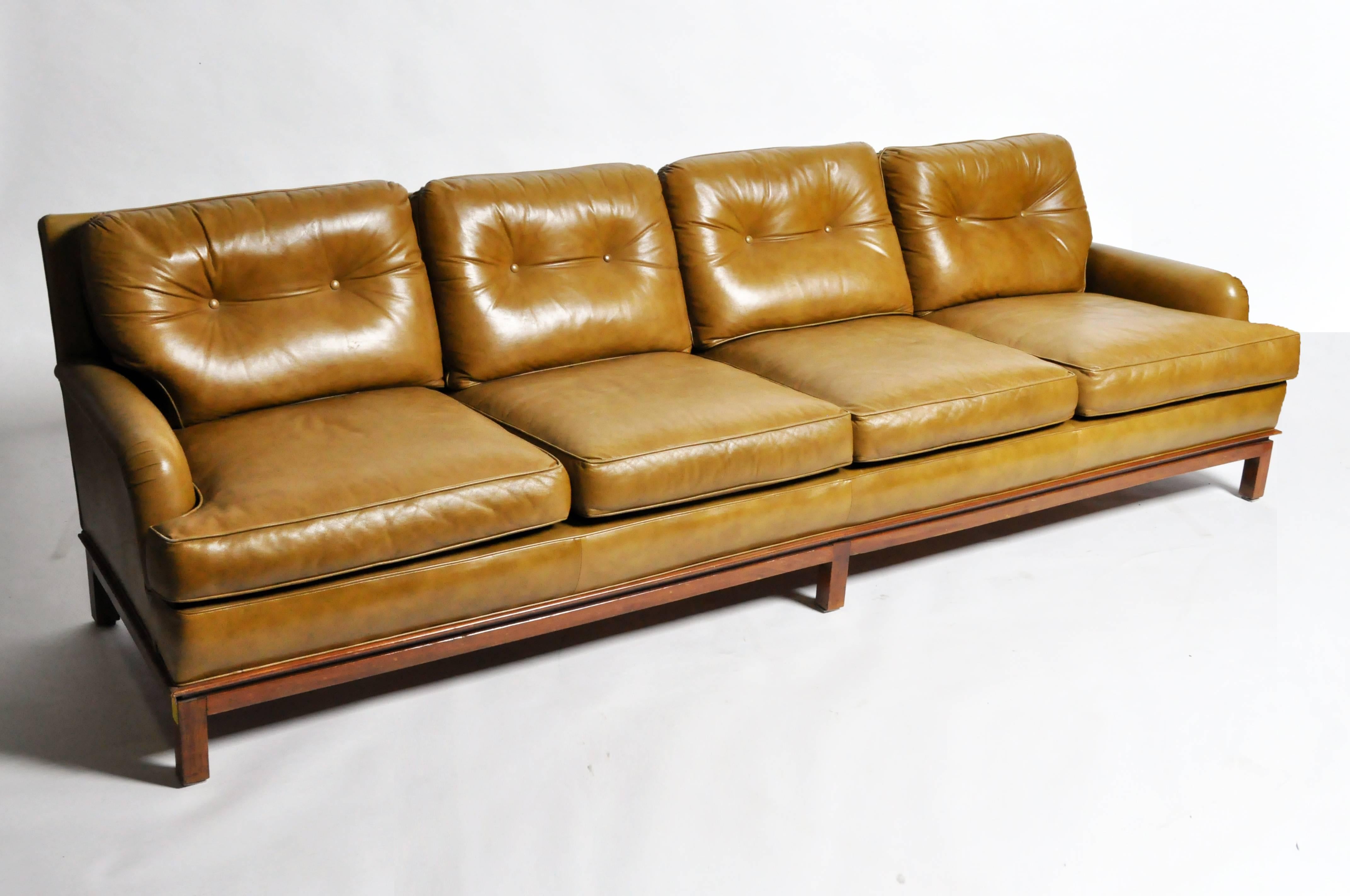 This handsome green leather sofa with hardwood base is from the United States and was designed in the style of Edward Wormley, circa 1960. Low-slung and highly comfortable, the sofa's wooden base gives it a strong visual presence that is unusual in