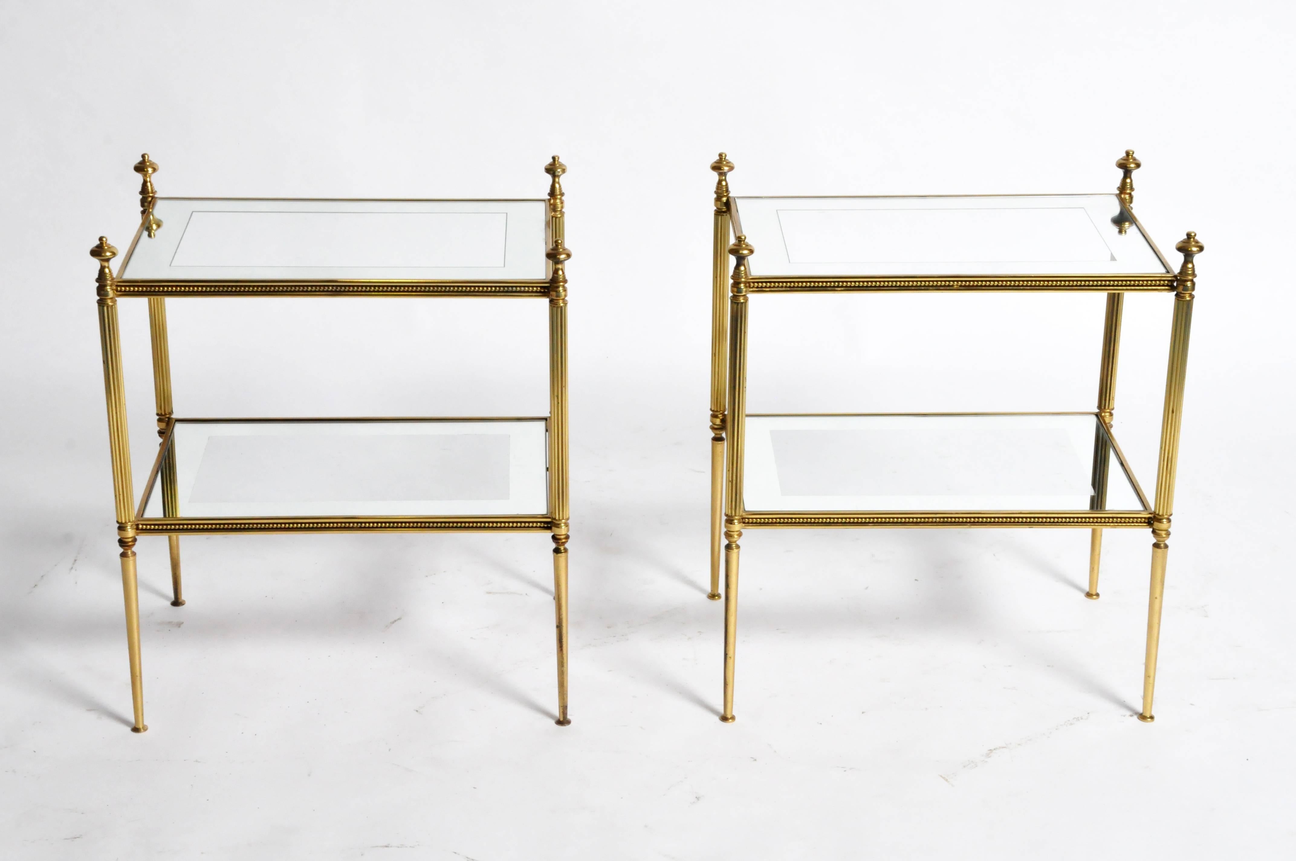 This pair of Mid-Century Modern side tables are from Paris, France and was made from brass and glass, c. 1950. The tables feature two mirrored glass shelves around the boarder of the glass. Great additions to any room in your home. 