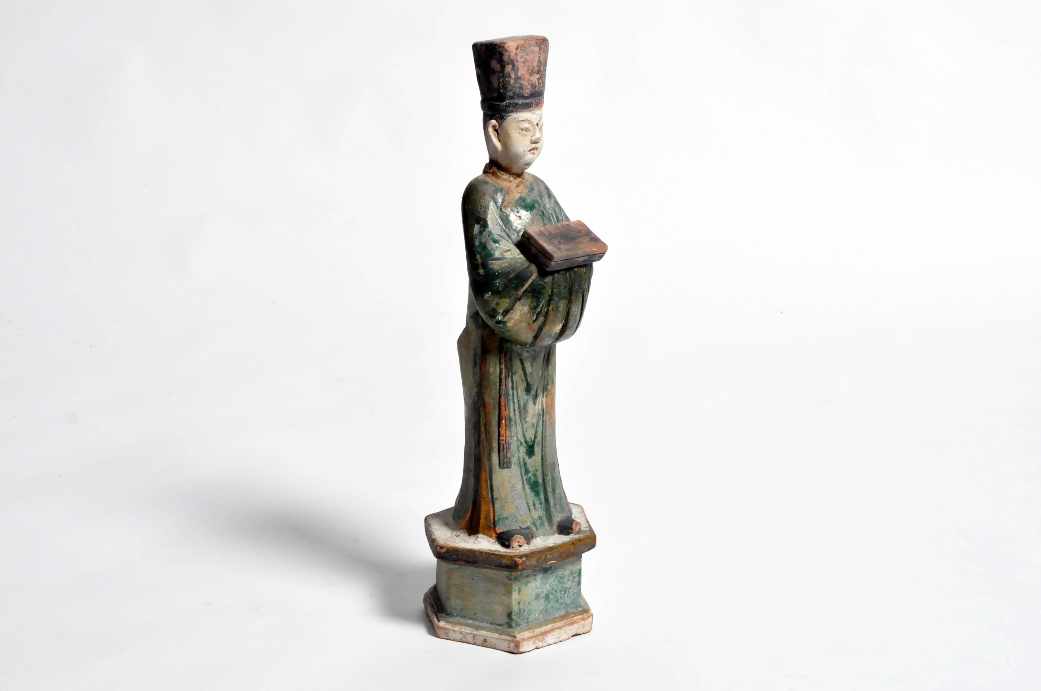 This green glazed terra cotta figure of an attendant is from the Ming Dynasty (1368 – 1644). The piece features an excellent iridescent patina with repair to neck.