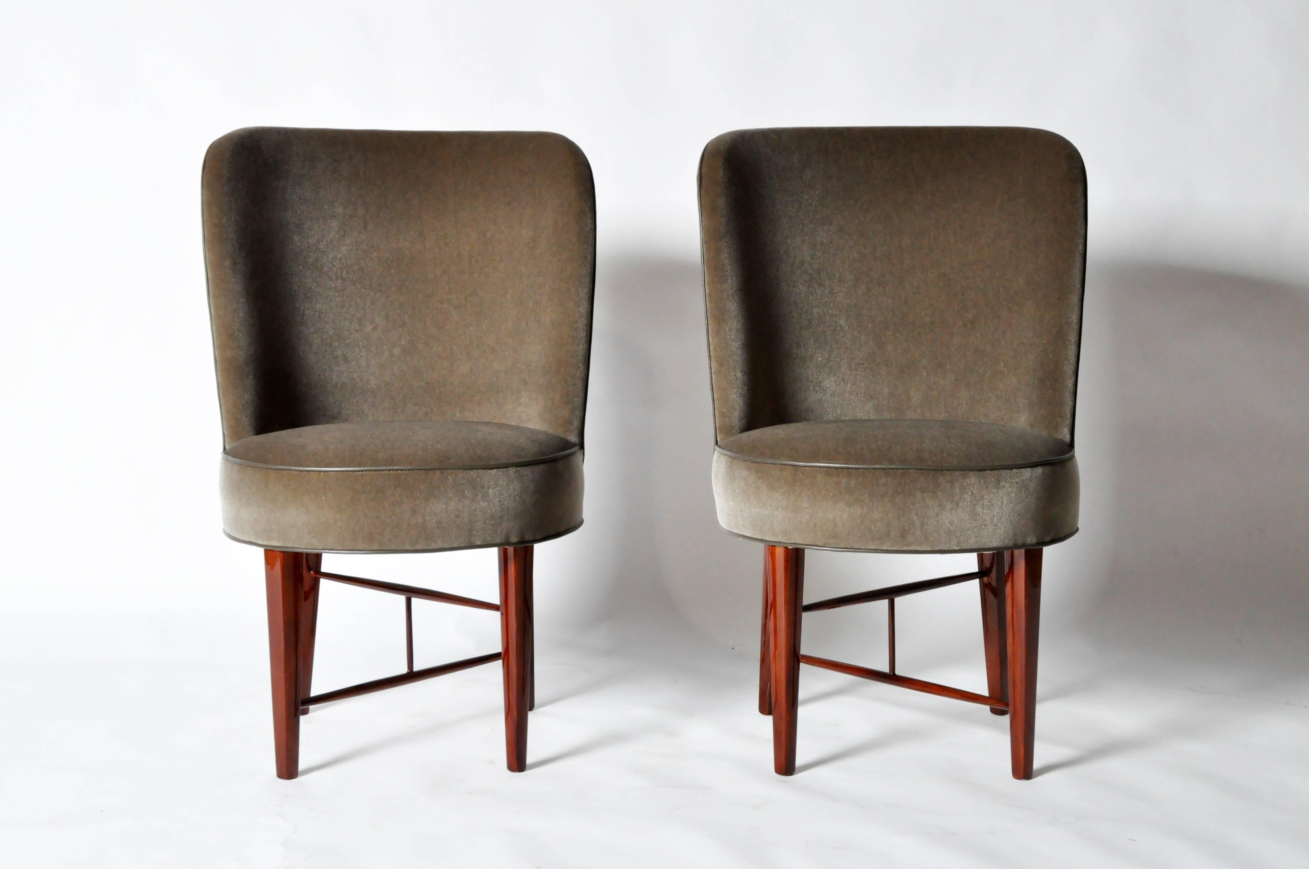 Having curved upholstered backs and seats, raised above solid walnut legs and X-form stretchers.