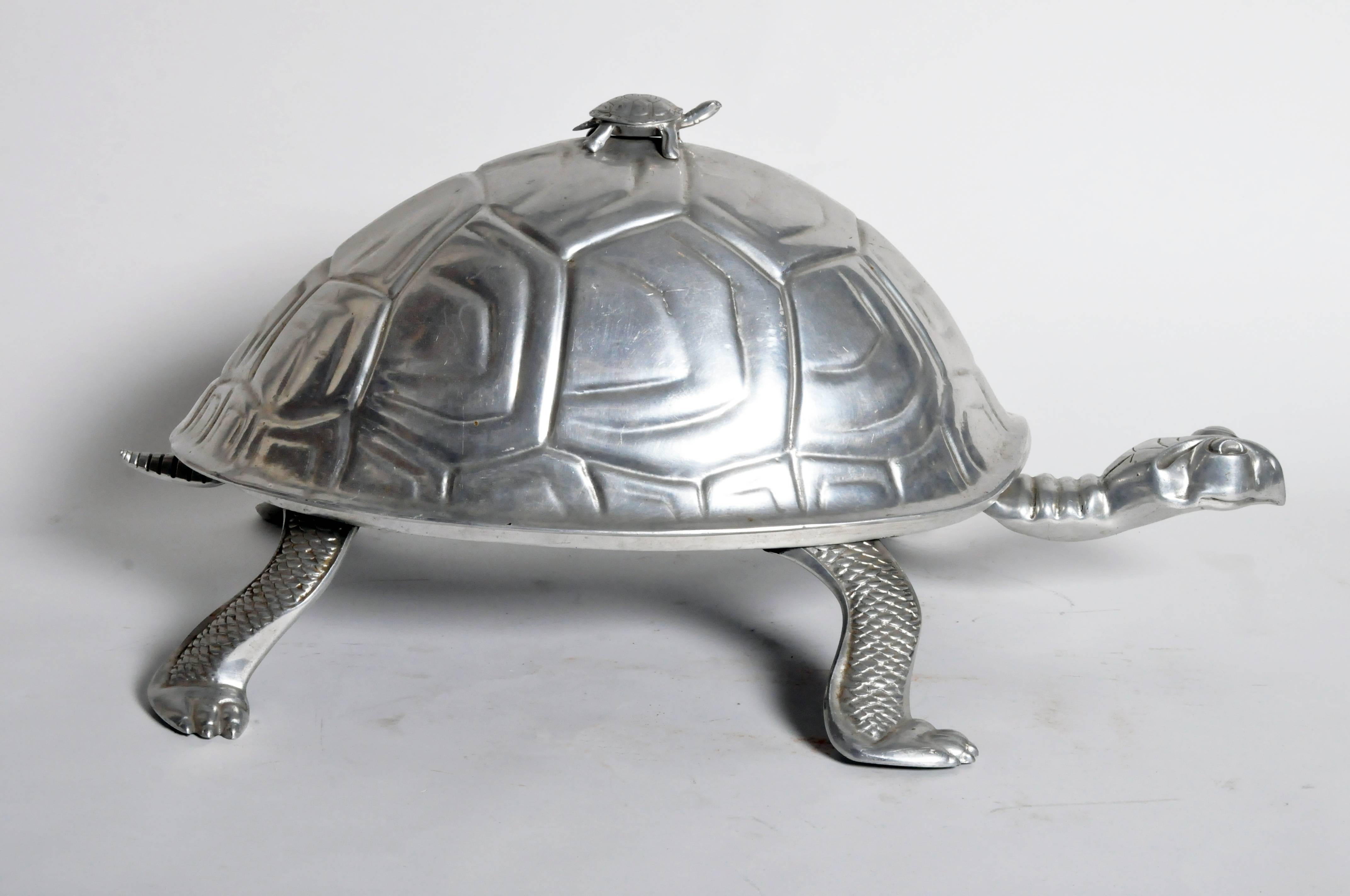 In the form of a tortoise, this slow and steady creature becomes spacious centerpiece for a savory roast or bird. A removable wood carving board rests underneath the shell-form lid, which has a smaller tortoise-form finial.
