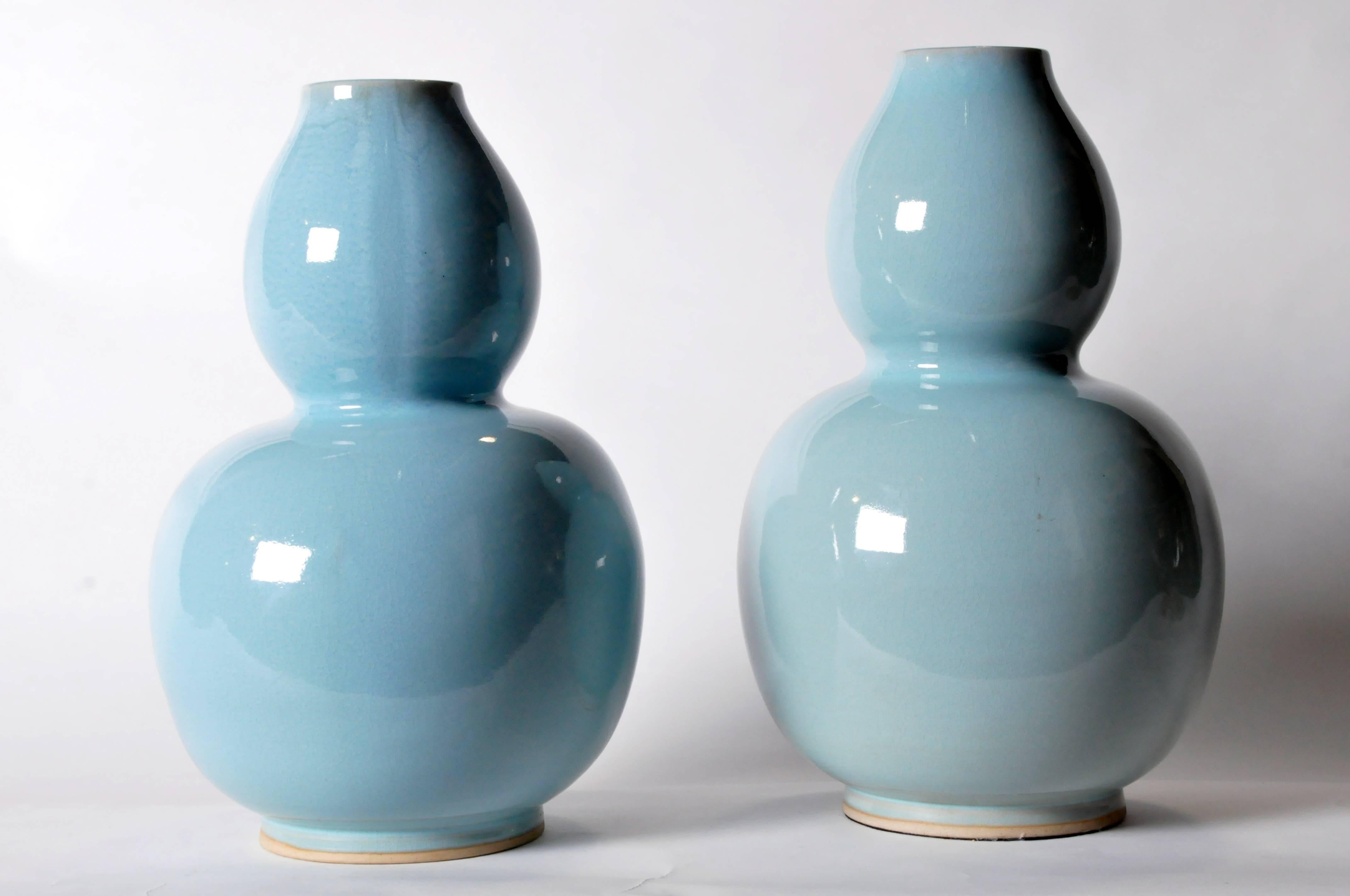 Dramatic on its own or paired with another, this curvaceous vessel is handmade and features a beautiful light blue glaze with a high-gloss crackle finish. Shown in a pair for comparison and styling; each is sold separately and has its own unique