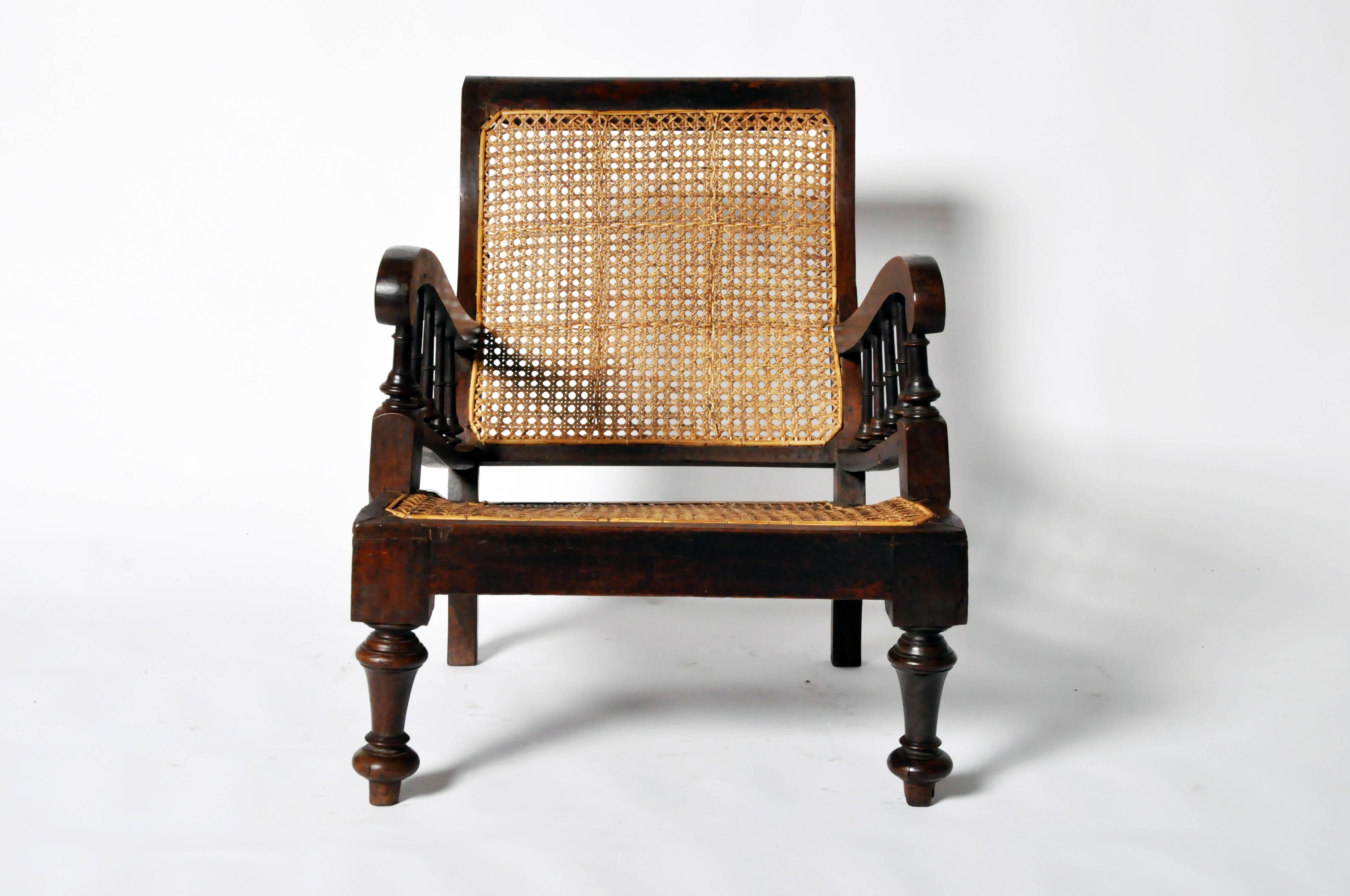 Constructed with lounge-like comfort in mind, the slightly reclined back and sloped seat feature handsome hole-to-hole traditional strand caning throughout. This relaxed armchair also has shapely arms supported by turned spindles, which mimic the