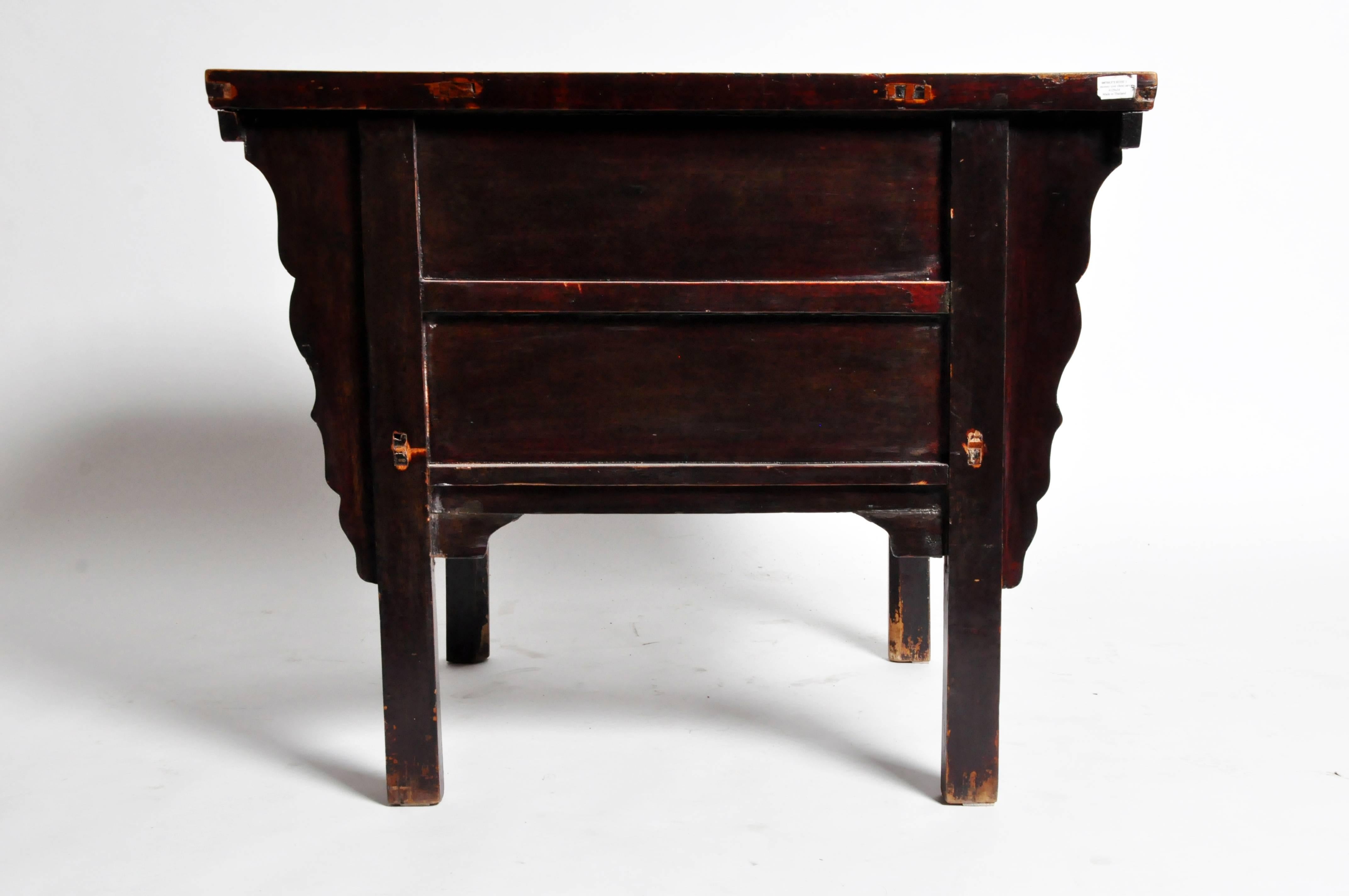 Handsome, warm wood and a well-worn maroon colored patina accentuate this side chest's mature aura. The sizable drawers sit above a relief carved center panel—decorated with a flowering branch—that conceals a hidden compartment (or ”menhuchu”). The