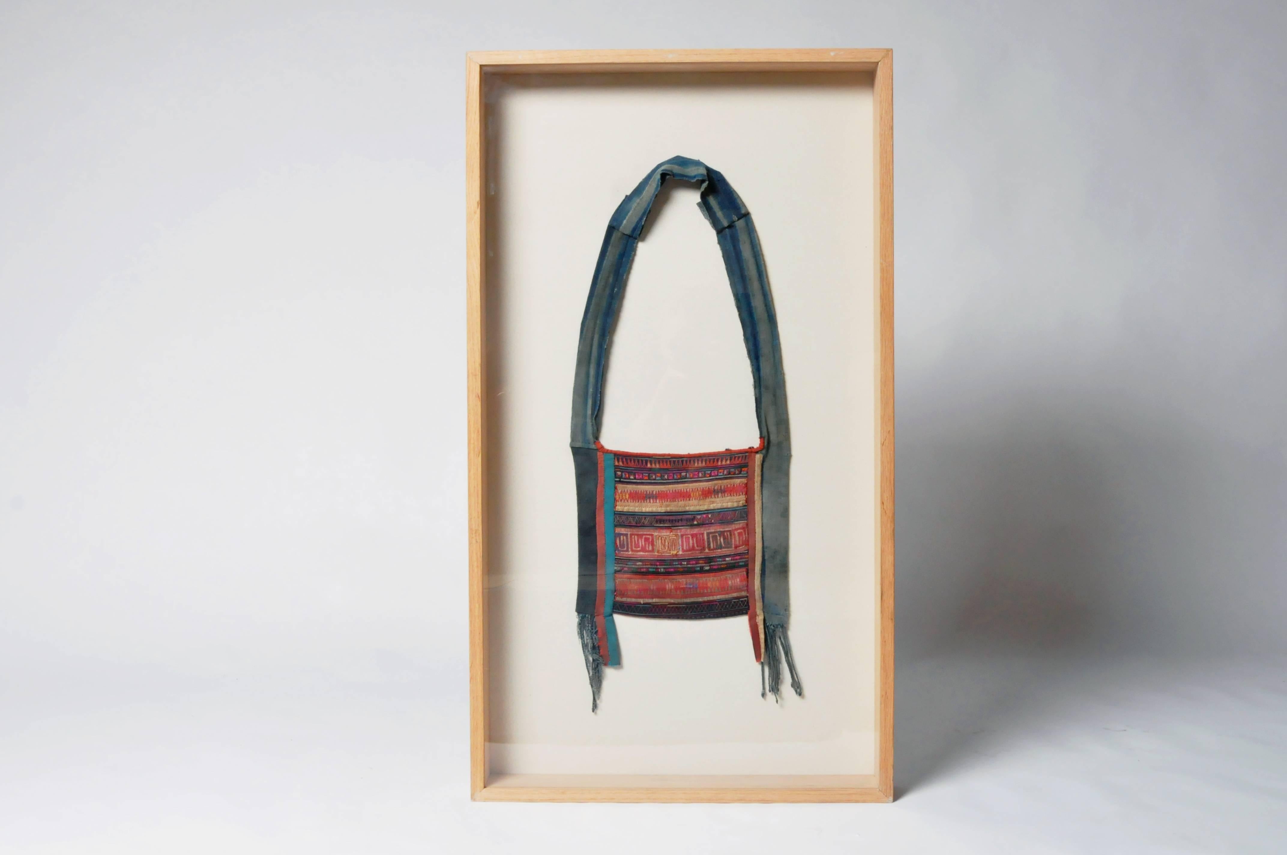 This hand embroidered shoulder is from the Akha tribe and has been framed for display on a wall. The Akha are an indigenous hill tribe who live in small villages at higher elevations in the mountains of Thailand, Burma, Laos, and Yunnan Province in