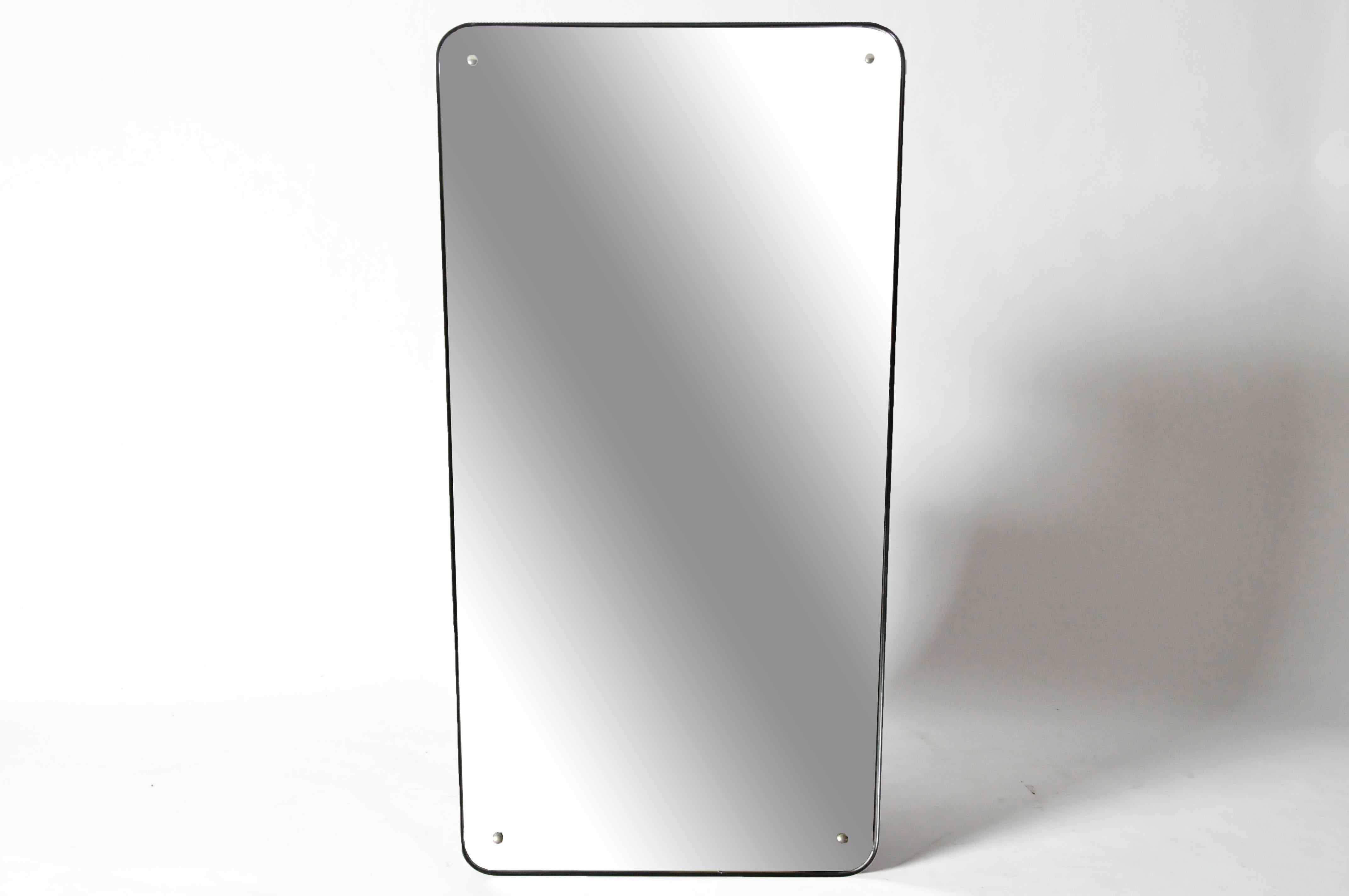 The large, tapered rectangular mirror plate has rounded edges and is outlined by a thin black wooden frame.