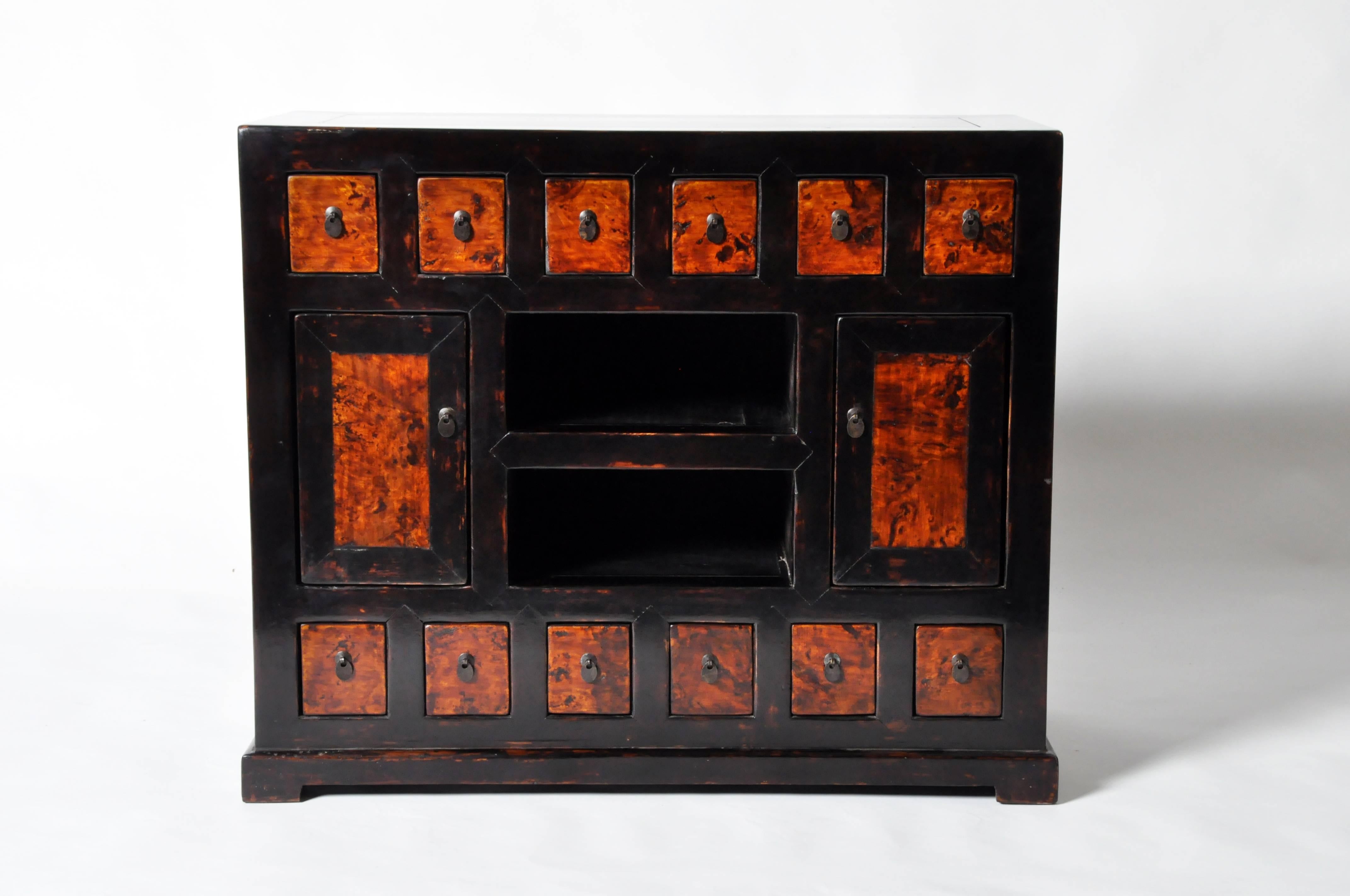 This Chinese Medicine chest is made from elmwood and has been fully restored. It features two display shelves and 12 drawers for ample storage.