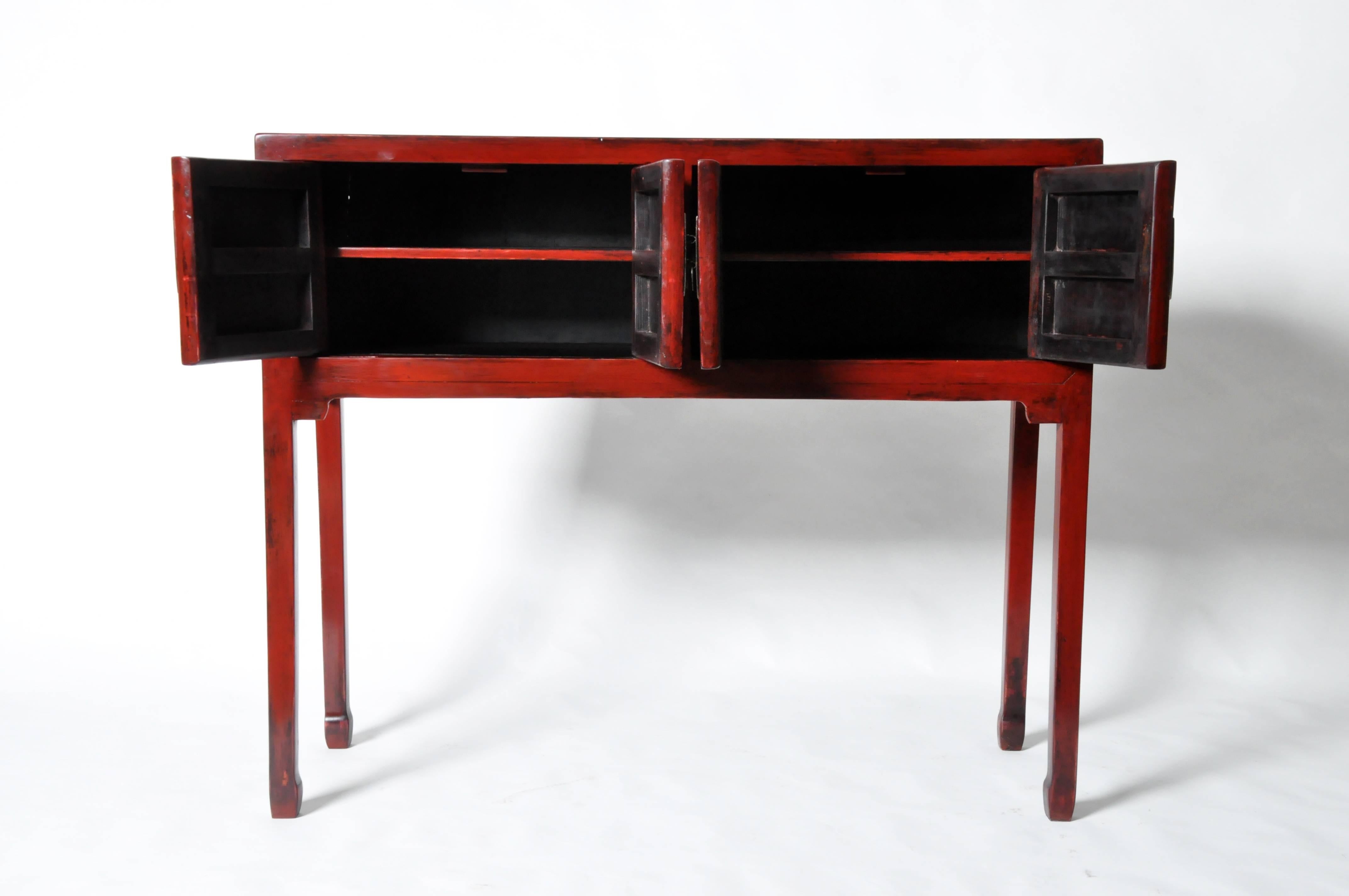 This Chinese red lacquered chest is made from elmwood and lacquer. It features two shelves for storage and has been fully restored.