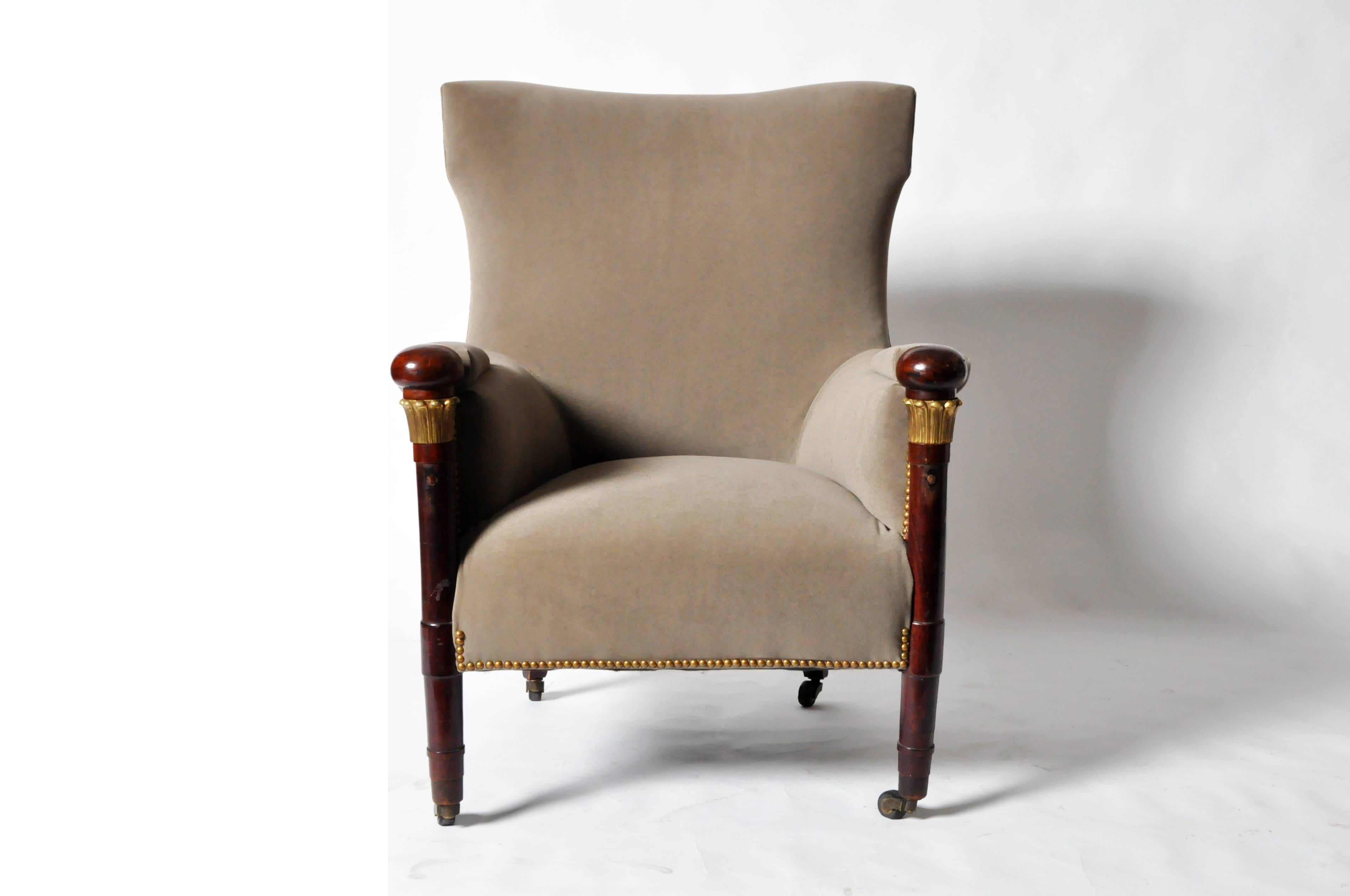 This comfortable chair features a pair of column-form front legs raised on casters; each has a decorative acanthus capital-like band below the ball top.