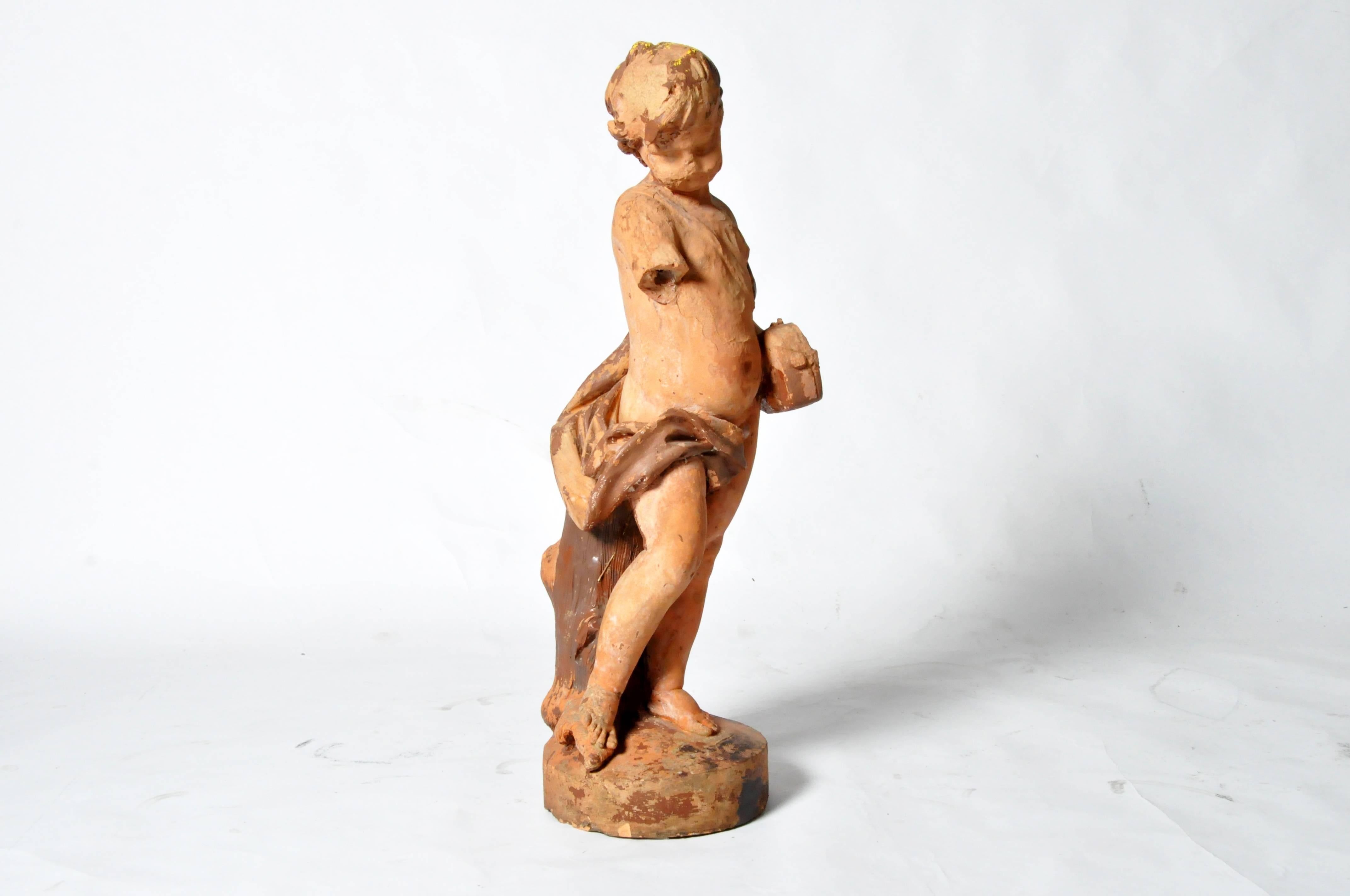 This beautifully weathered sculpture depicts a standing boy, cradling his violin. Some of the original pigment and sculpted decorations are still visible.