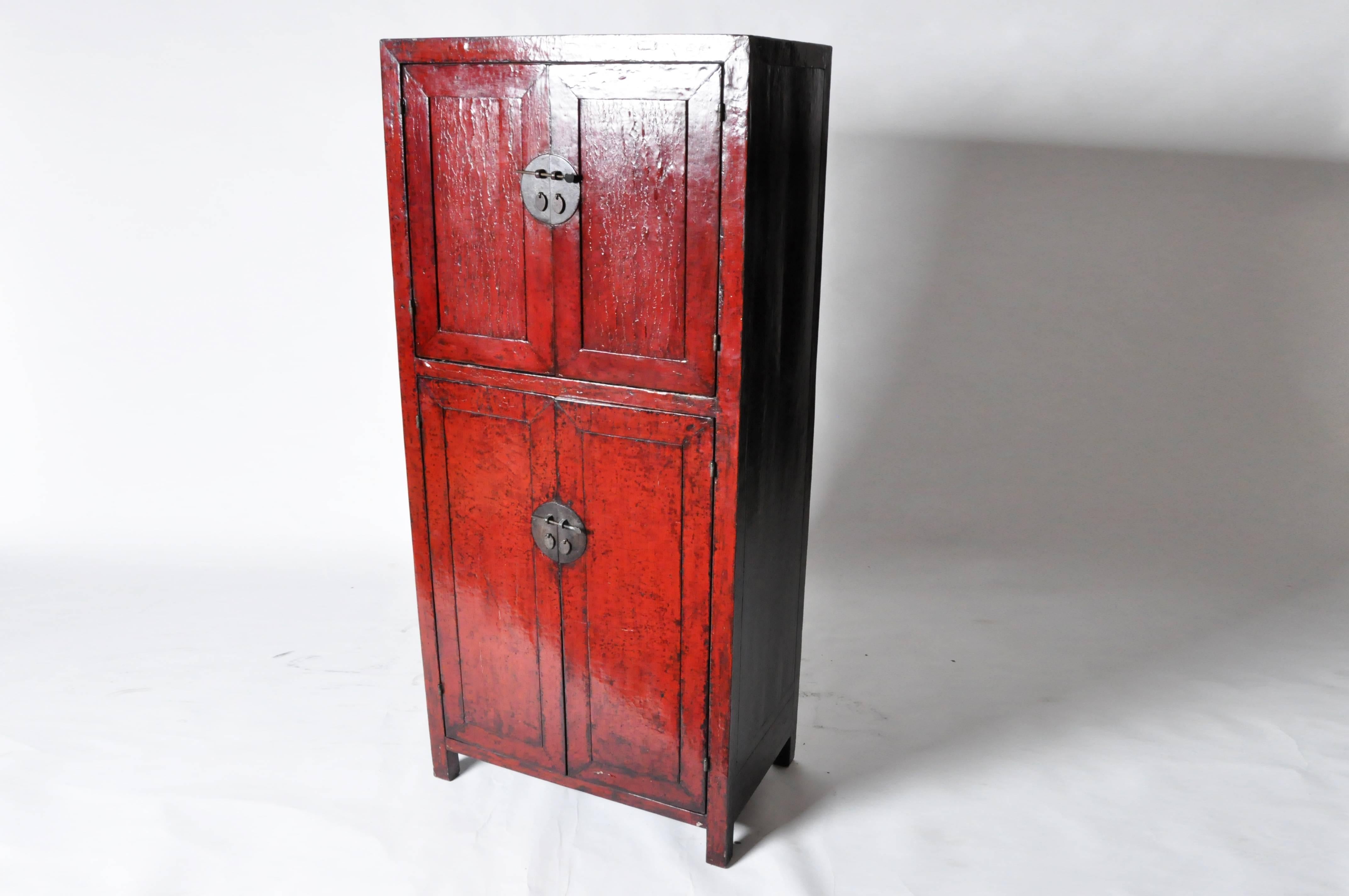 This red lacquered Chinese cabinet is made from elmwood. The piece features three shelves for storage.